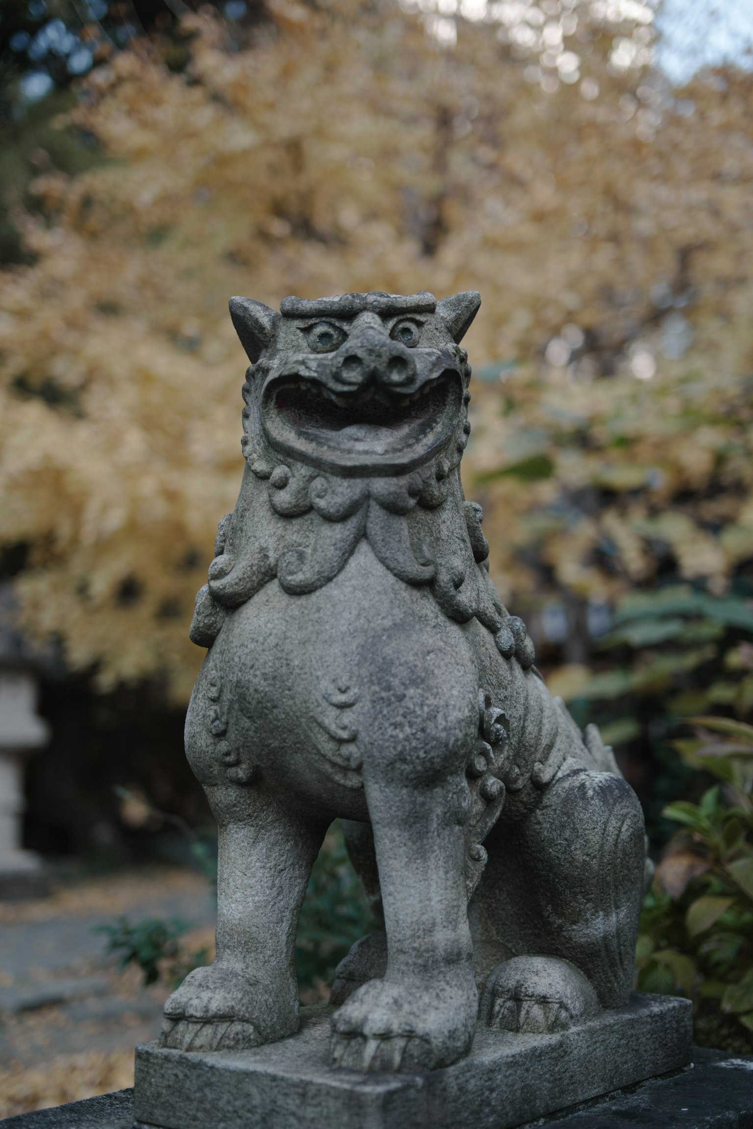 Statua di leone in pietra che si erge tra il fogliame autunnale