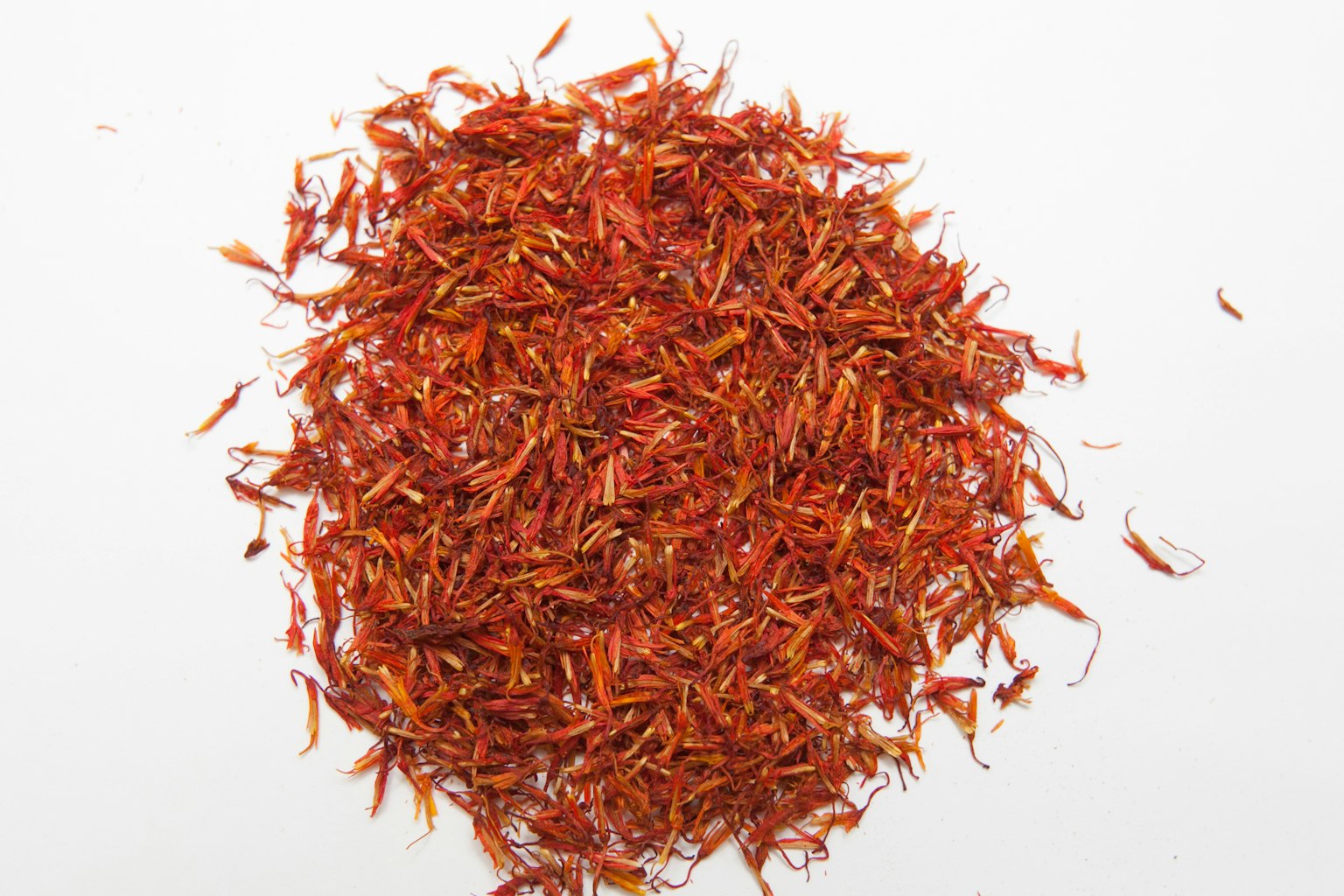 Vibrant red saffron threads scattered on a white background