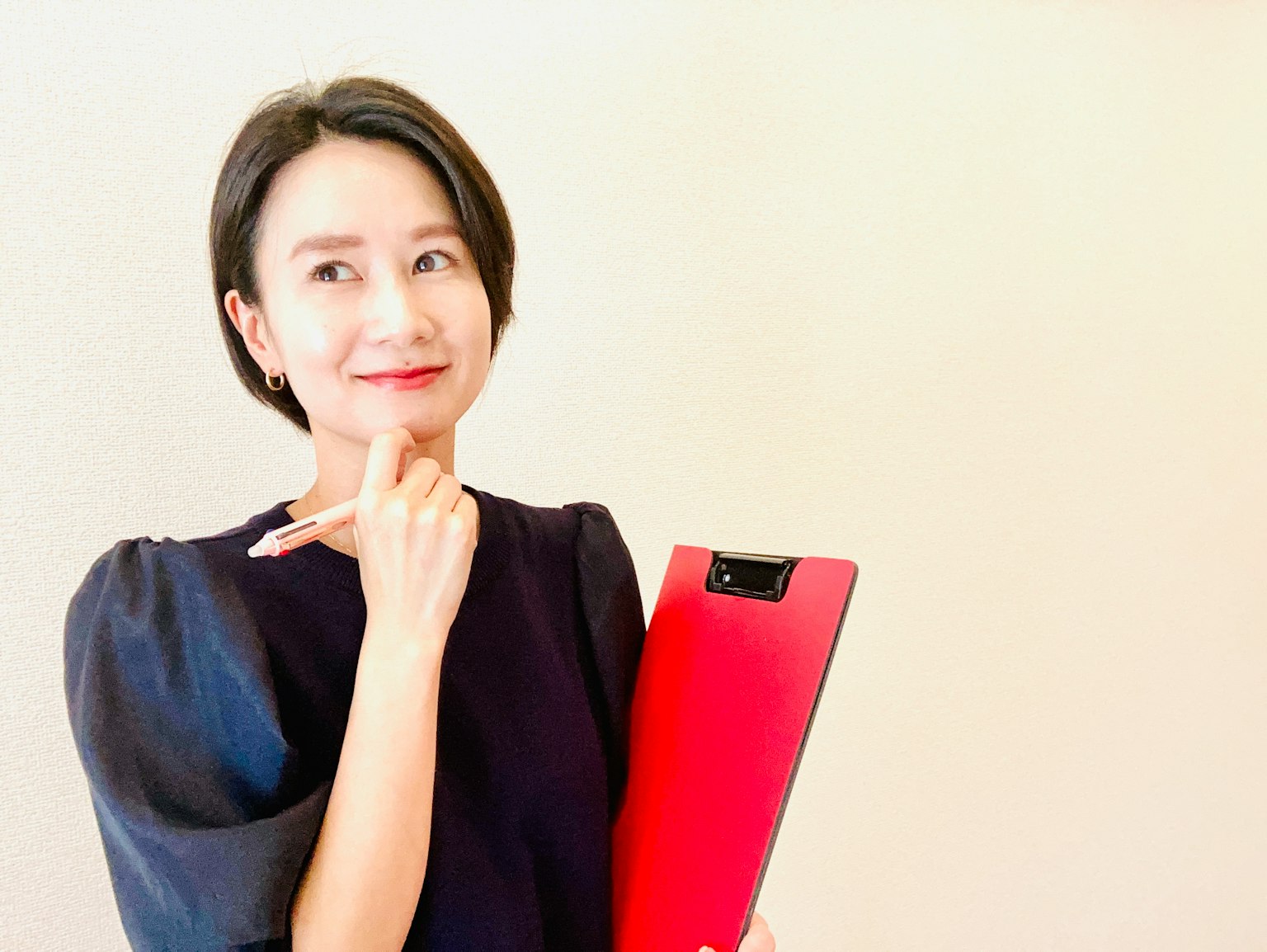 Người phụ nữ đang suy nghĩ trong khi cầm bảng kẹp đỏ