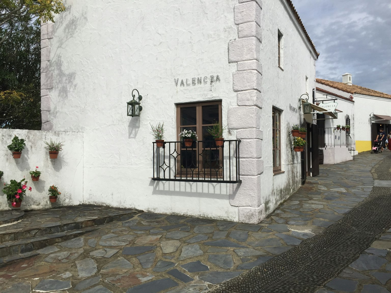 Bâtiment blanc avec fenêtres ornées de fleurs et chemin en pavés