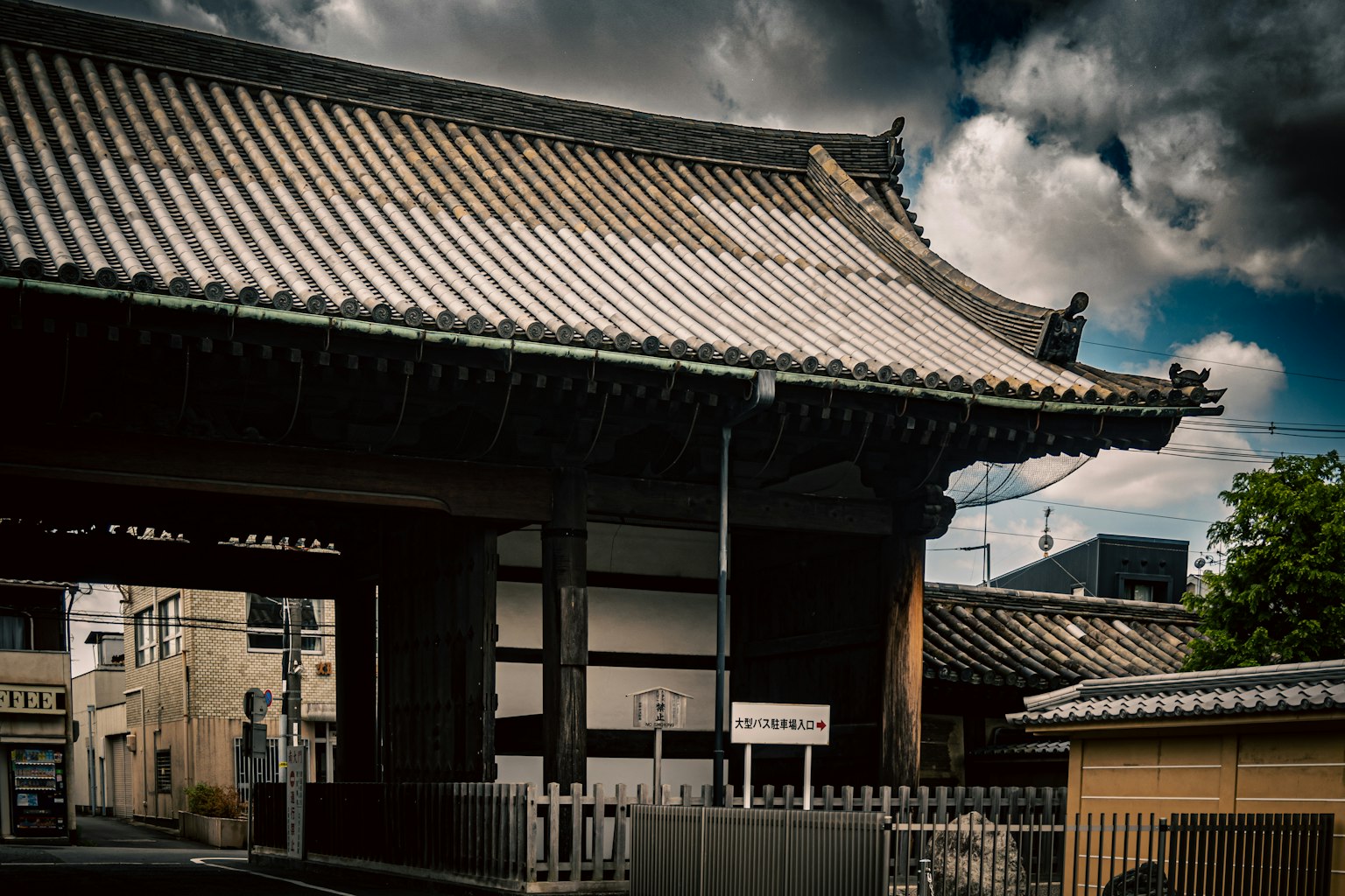 Porte de temple japonais traditionnel avec un toit courbé élégant et des tuiles, nuages sombres en arrière-plan