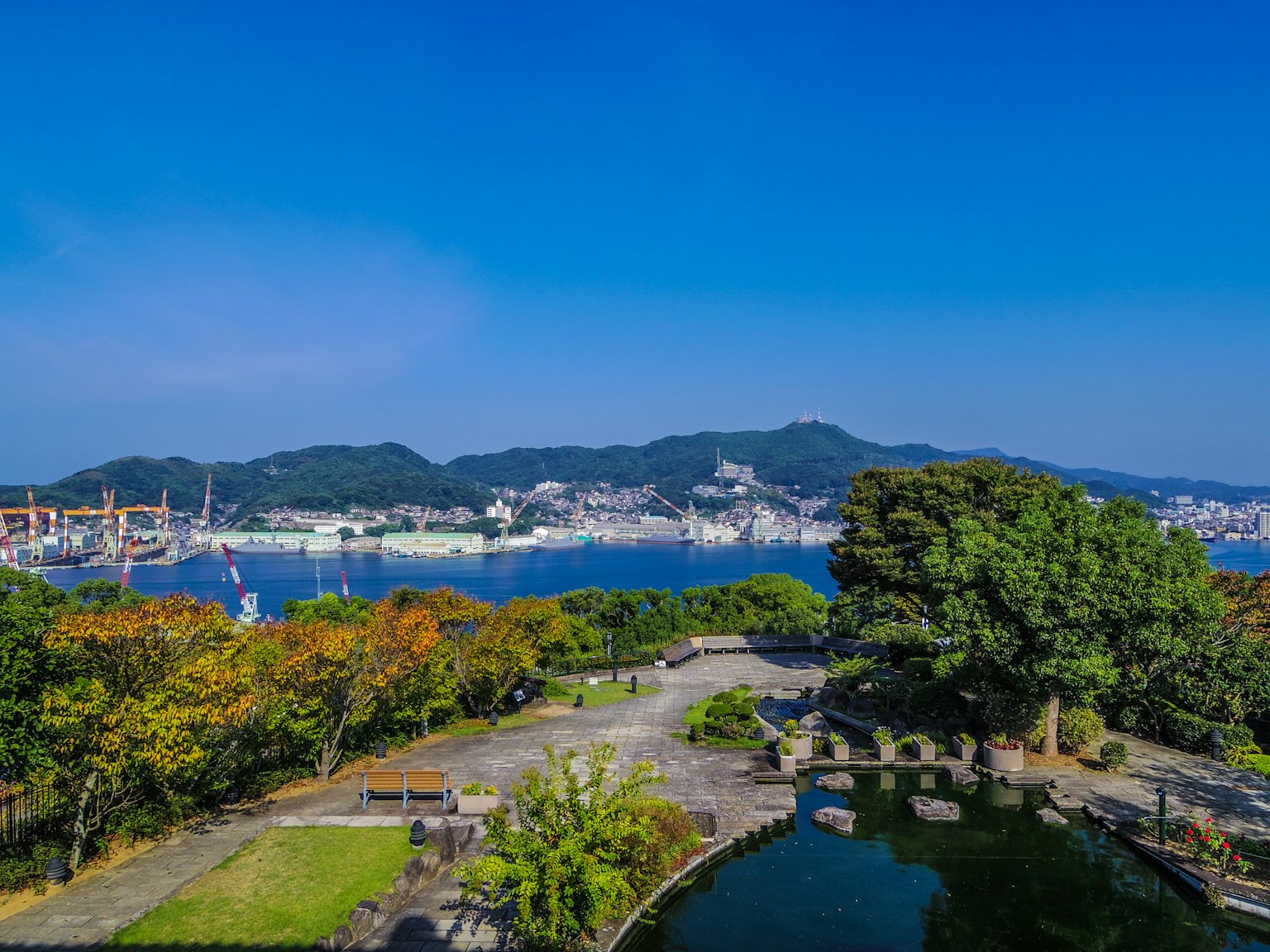 Scenic view of a harbor town surrounded by blue skies and calm waters Vibrant green trees and park landscape