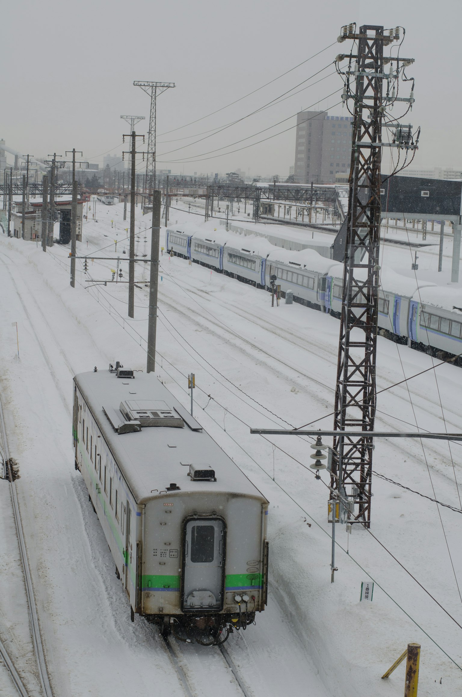 A snowy railway scene featuring a train and power lines