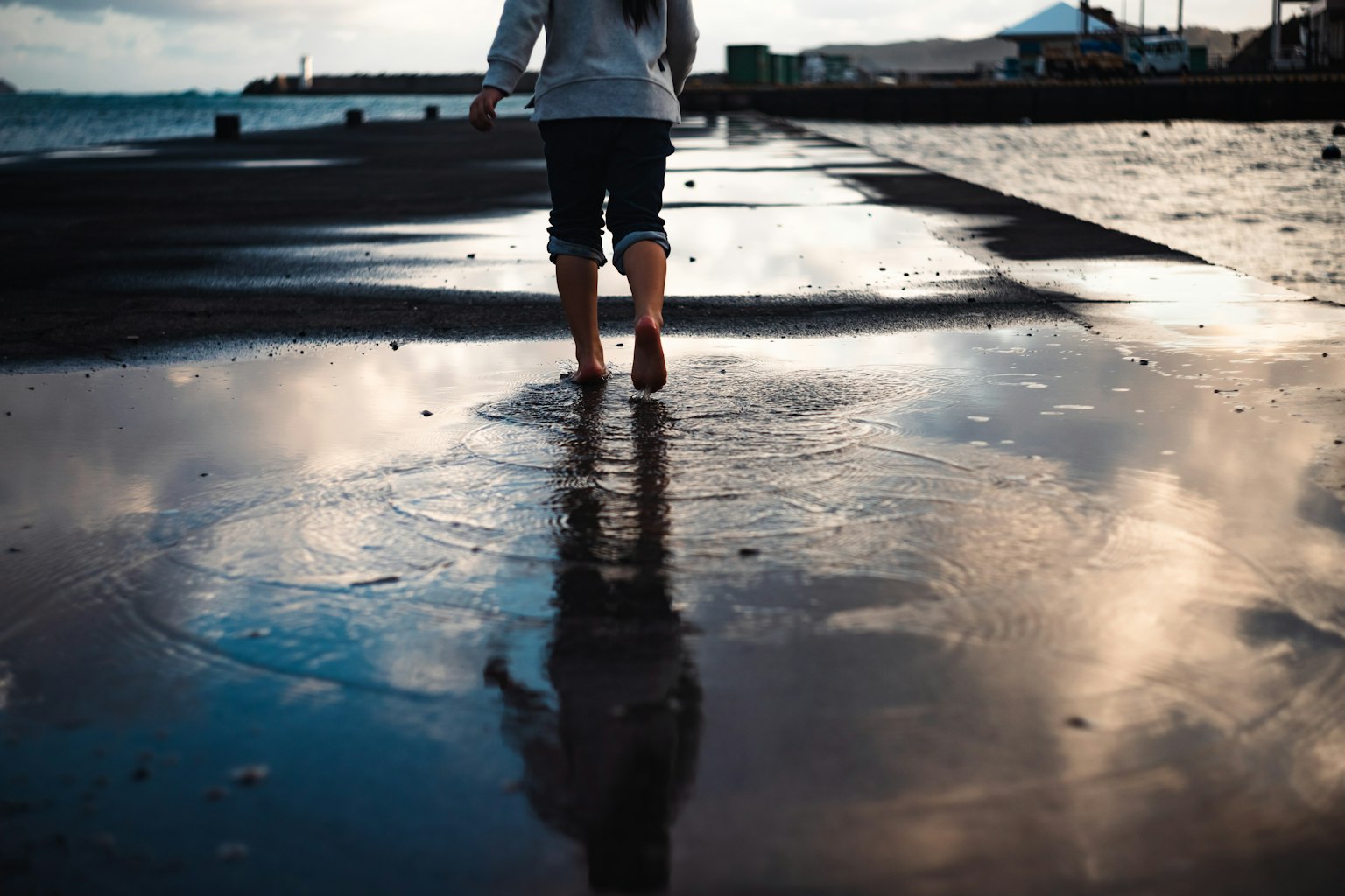 Silhouette of a person walking near the waves with reflections on the water surface
