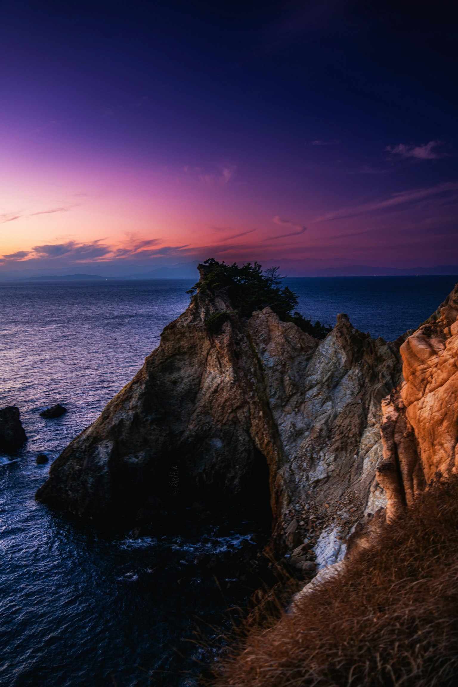 Impresionante costa rocosa silhoueteada contra un vibrante cielo al atardecer