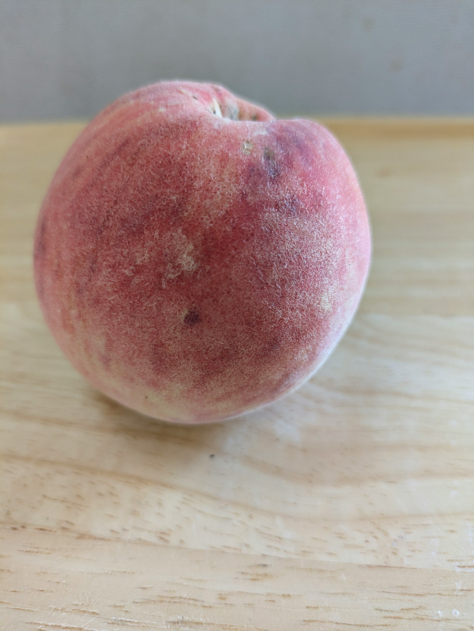A vibrant peach resting on a wooden table