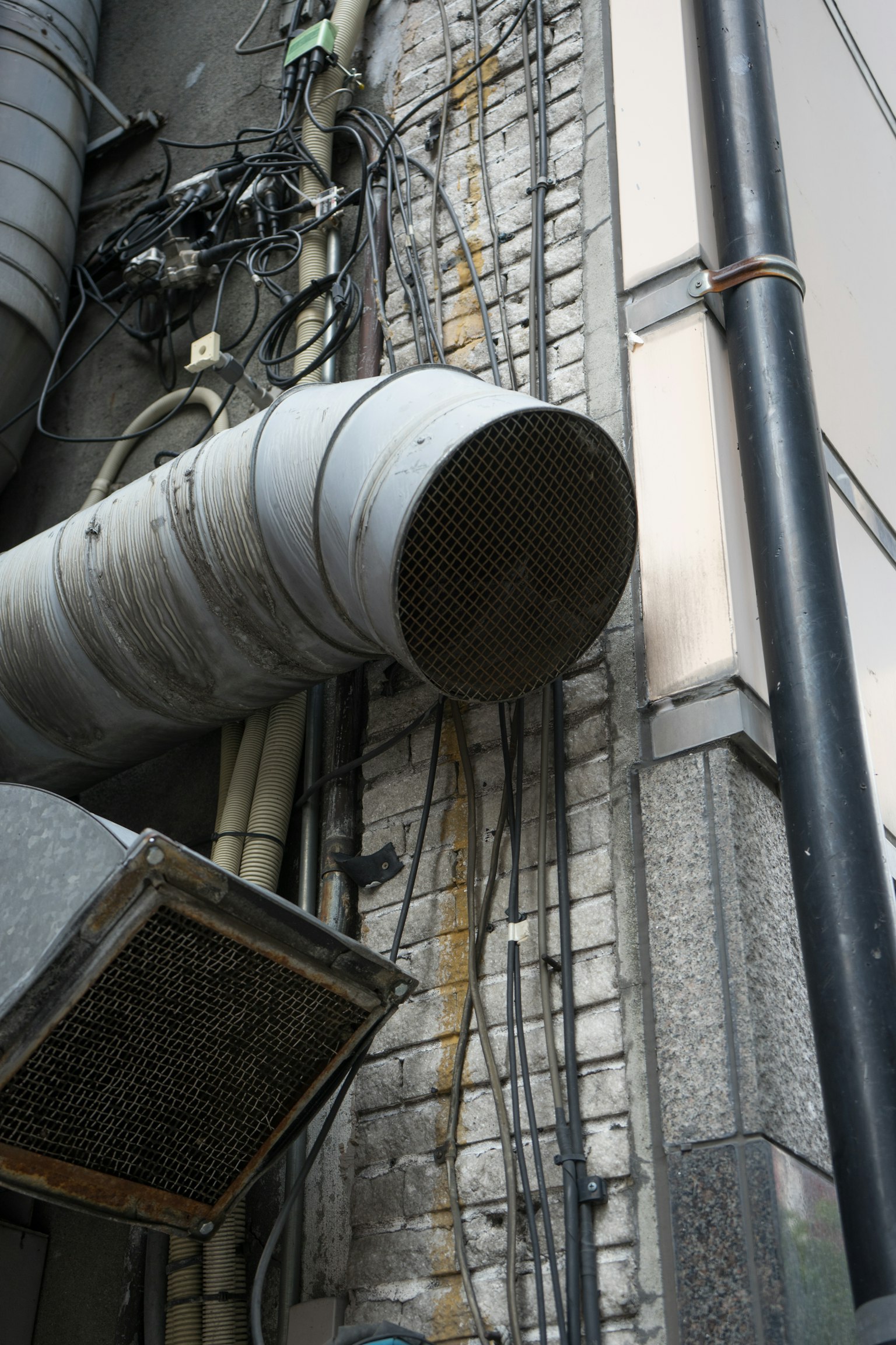 Scena industriale con un grande tubo di metallo e cablaggi disordinati attaccati a un muro