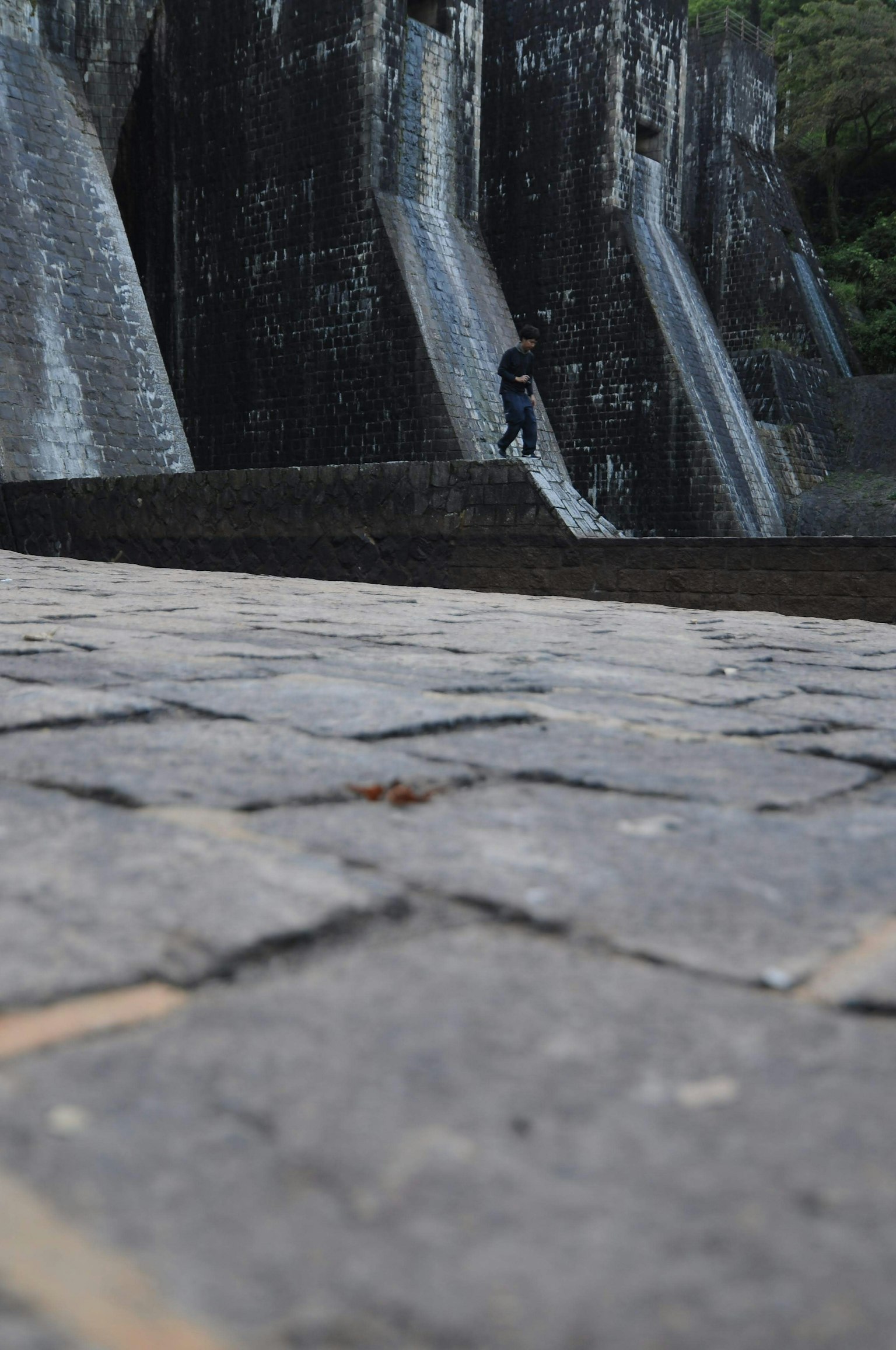 Person standing on cobblestone with ancient stone wall