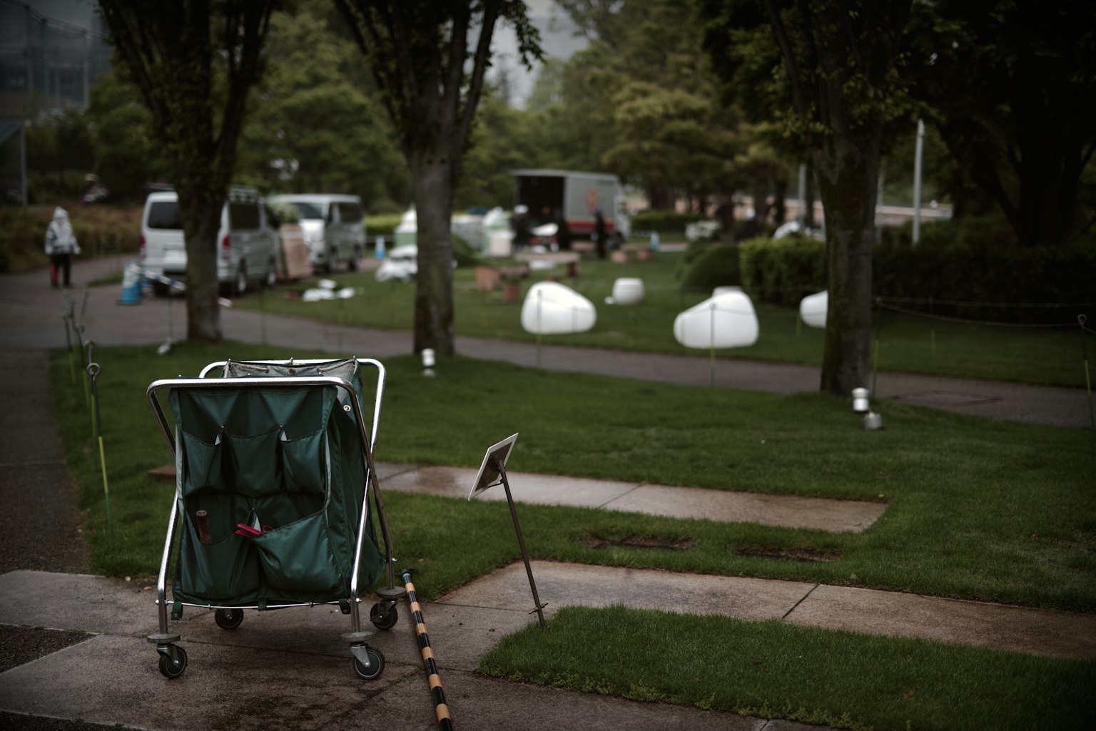 Grüner Kinderwagen auf Gras mit weißen Objekten im Hintergrund