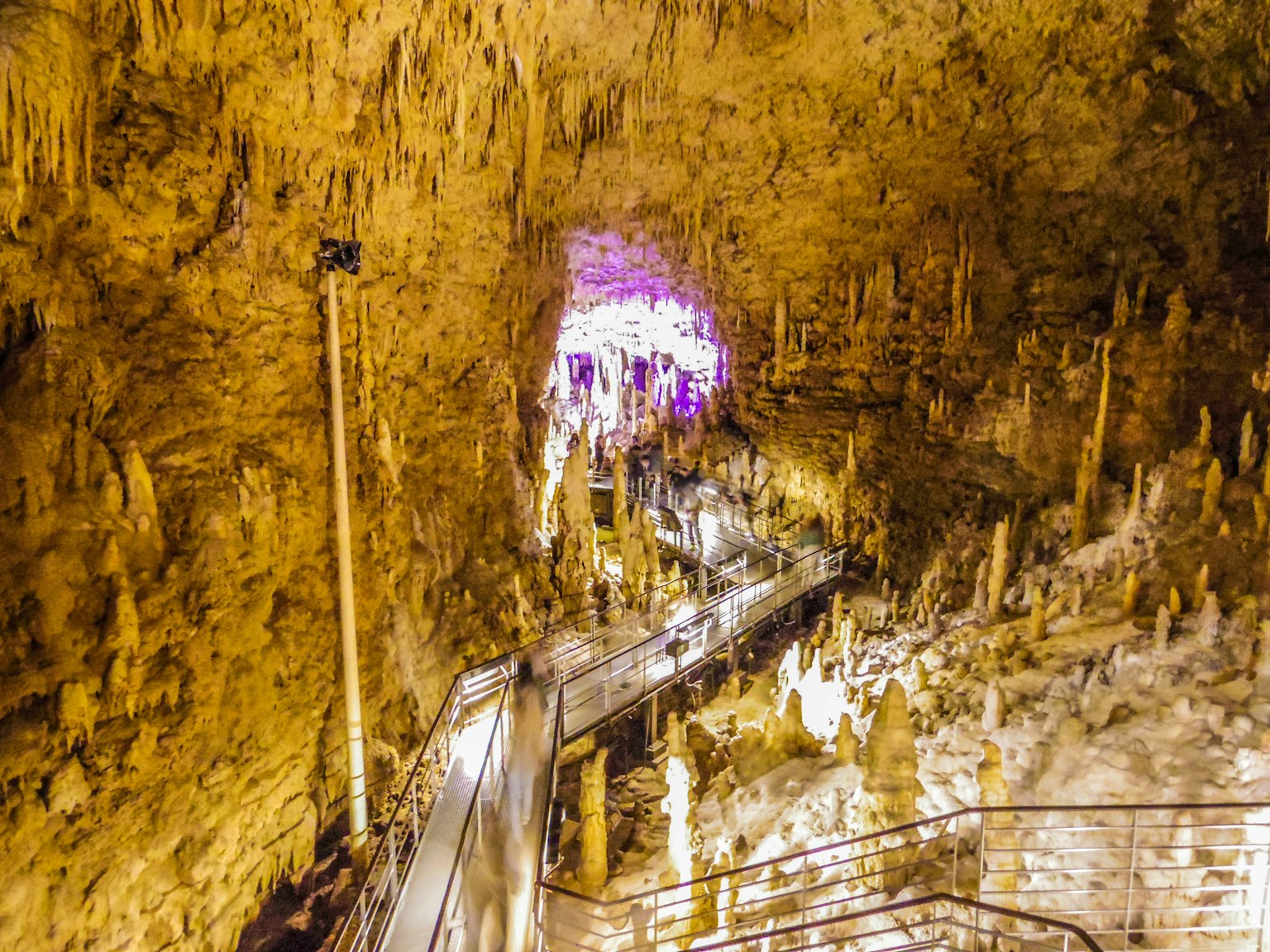 Vue intérieure d'une grotte avec des stalagmites et stalactites présentant des formations complexes et un éclairage artificiel