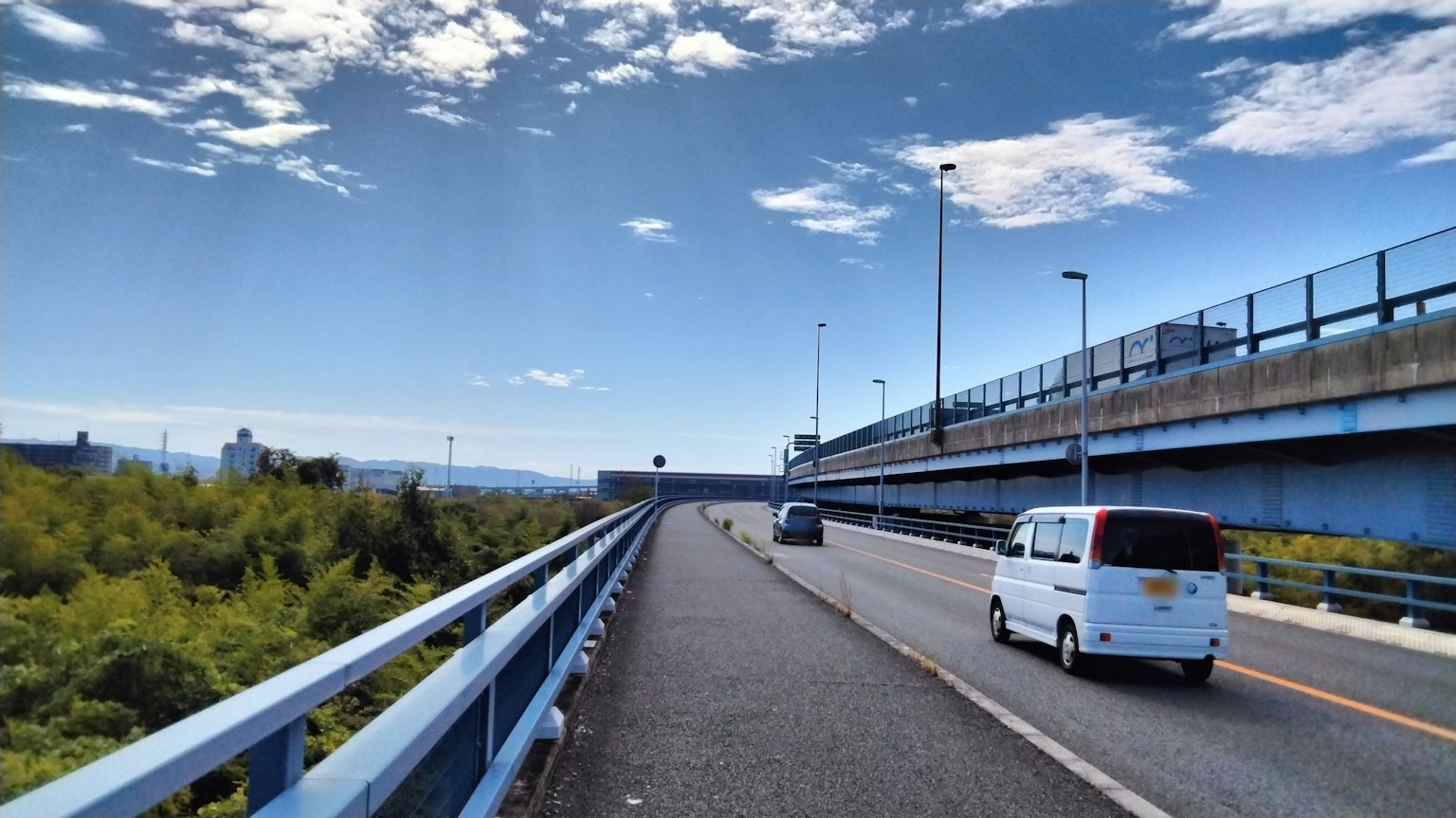Road view with blue sky and clouds featuring a passing vehicle