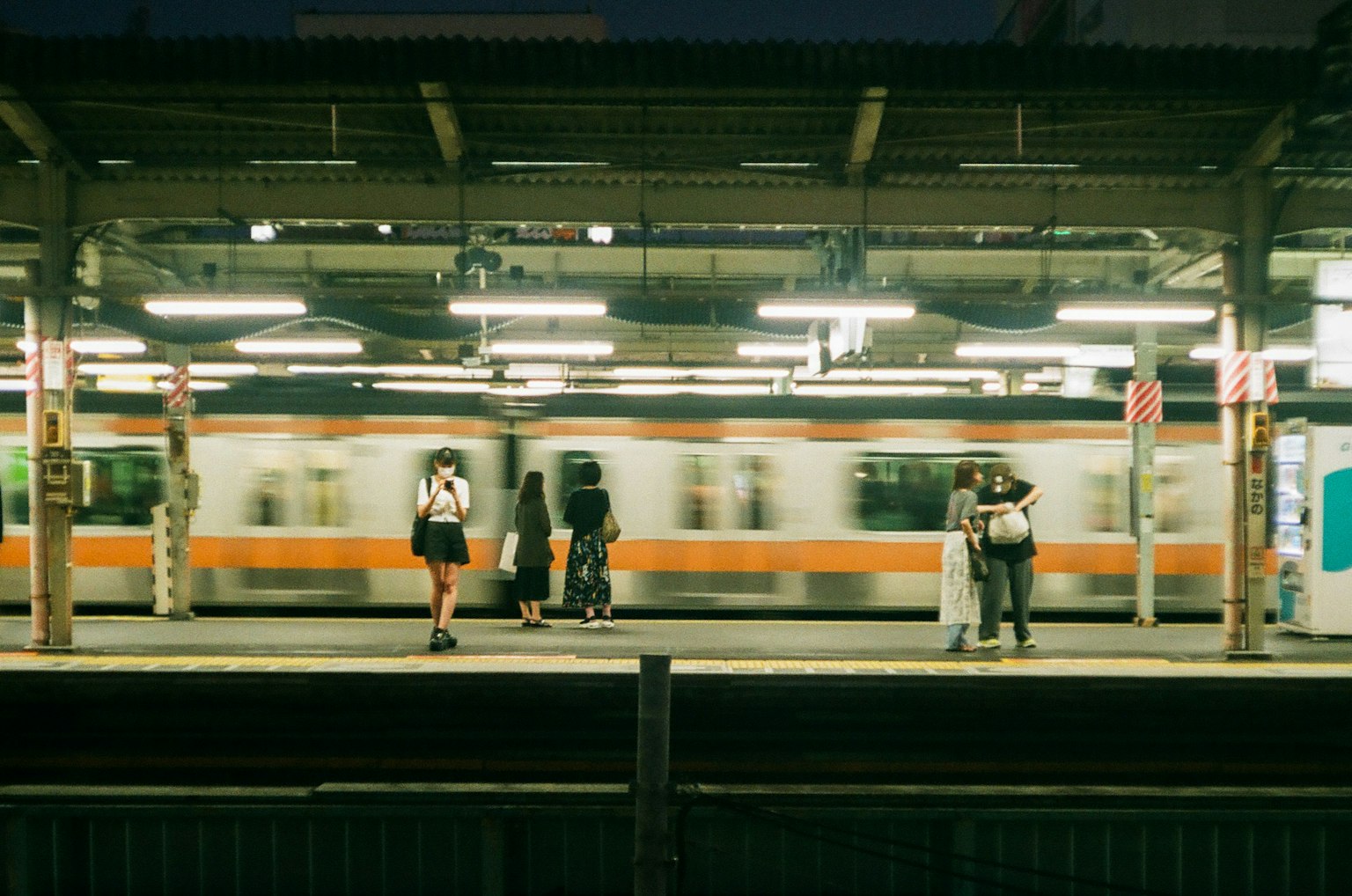Scène d'un train passant sur un quai avec des personnes attendant Lumières vives illuminent la zone