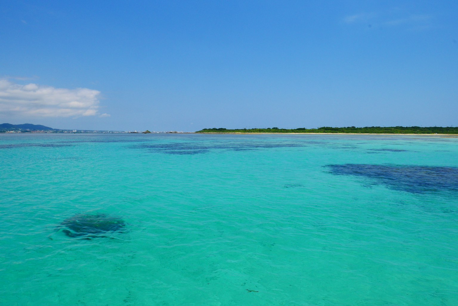 ทิวทัศน์ที่สวยงามของทะเลและท้องฟ้าสีฟ้าพร้อมเกาะสีเขียวในระยะไกล