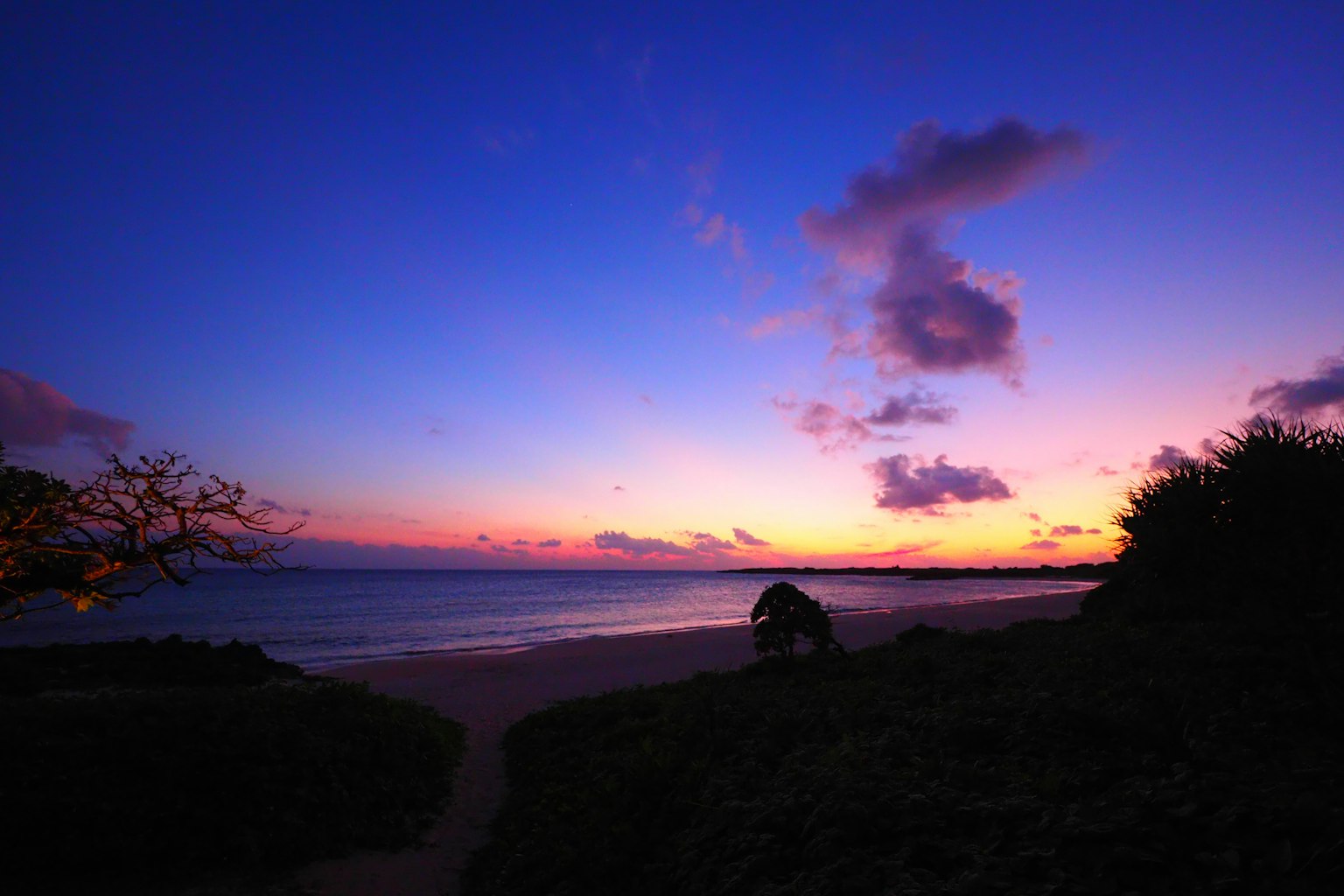 ทิวทัศน์ชายหาดที่สวยงามในยามพระอาทิตย์ตกท้องฟ้าสีม่วงและส้มเมฆในท้องฟ้า
