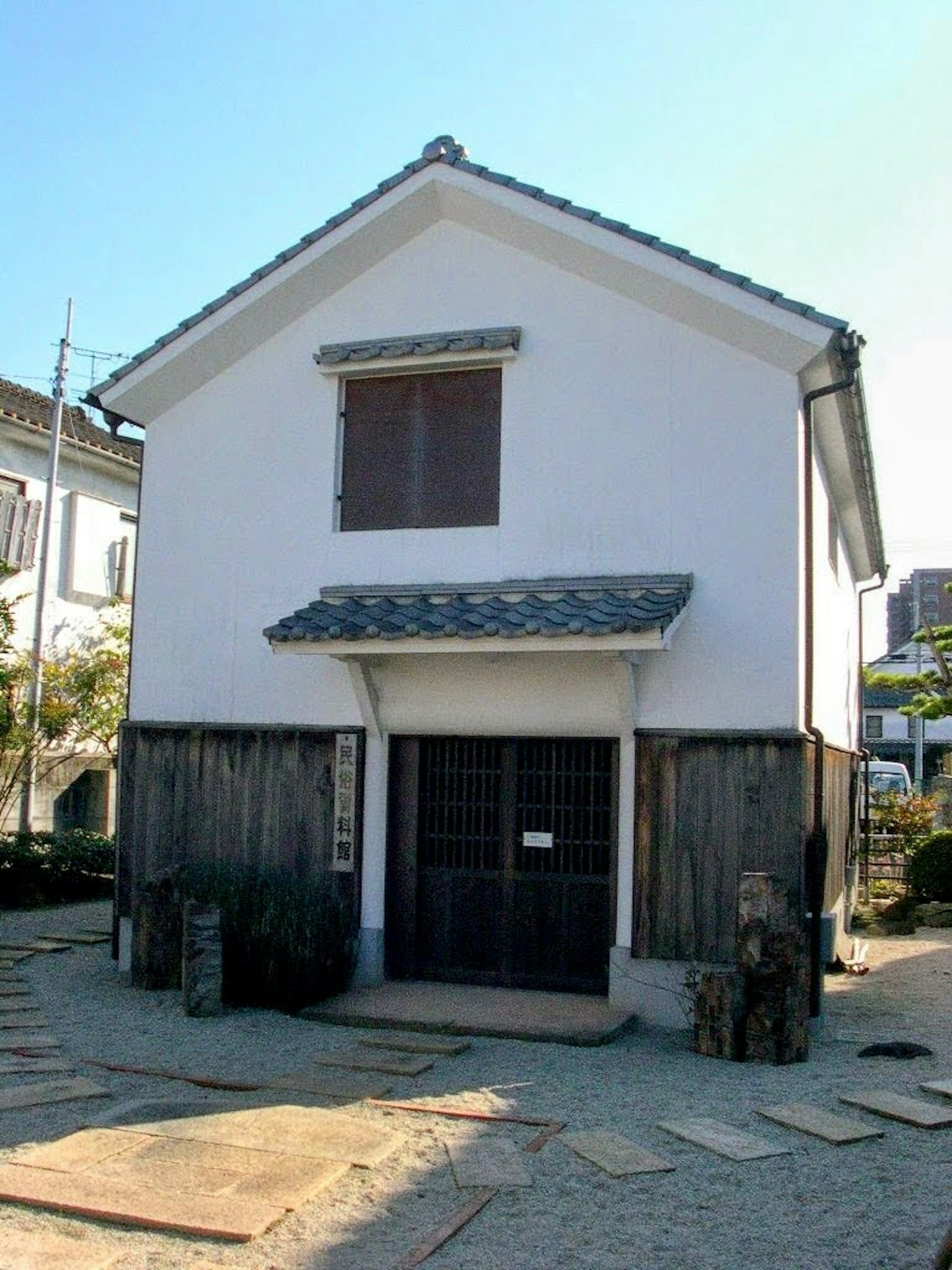 Rumah tradisional Jepang dengan eksterior putih pintu kayu dan atap genteng