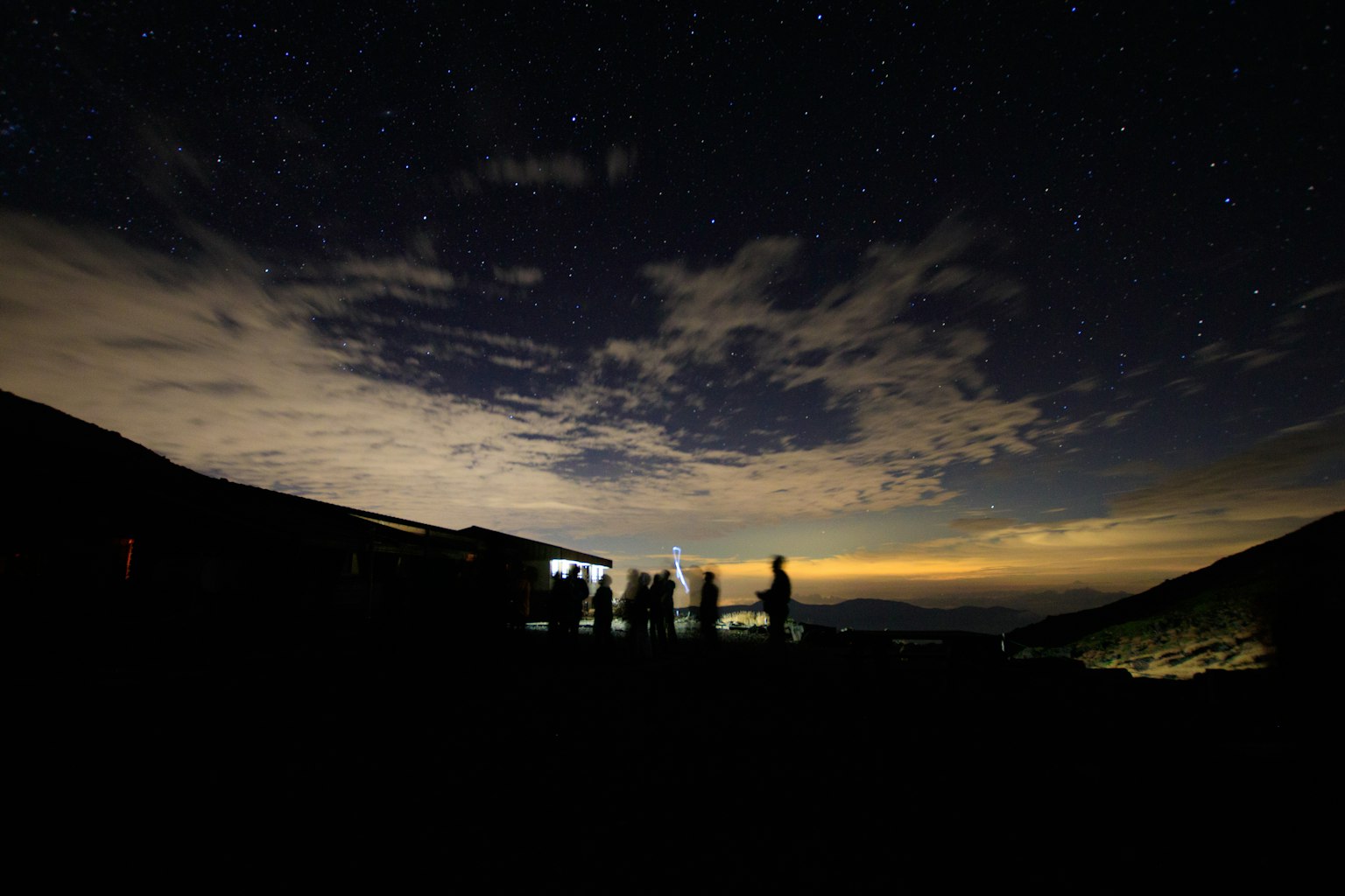 Silhouette de personnes contre un ciel étoilé et un paysage montagneux