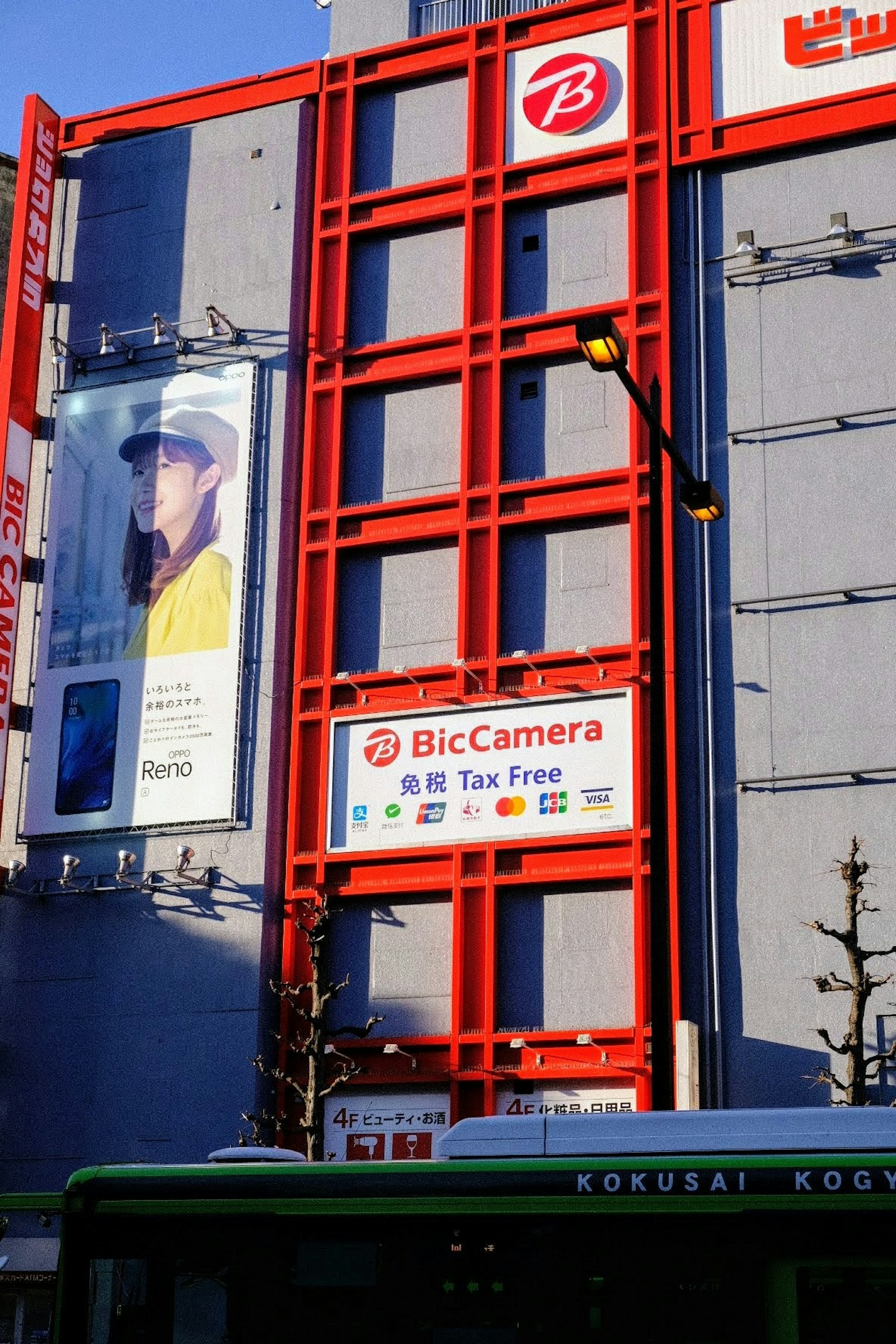 빨간 외관의 BicCamera 건물에 큰 광고가 표시되어 있음