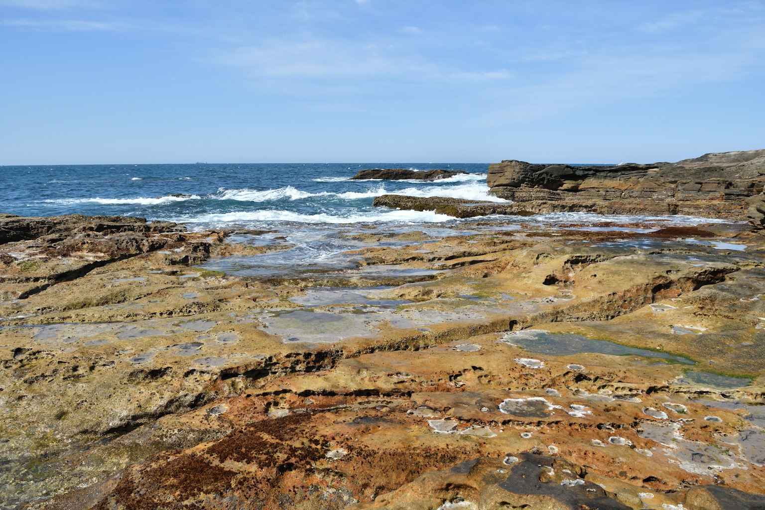 Pemandangan pantai dengan lautan biru dan tepi pantai berbatu