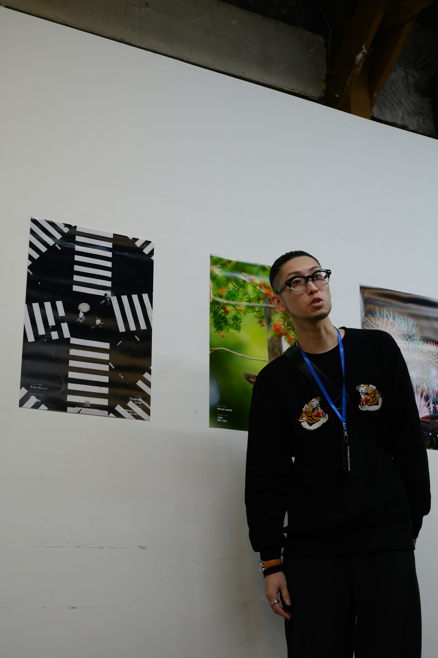 A man standing in front of wall art featuring black and white stripes and a nature scene poster