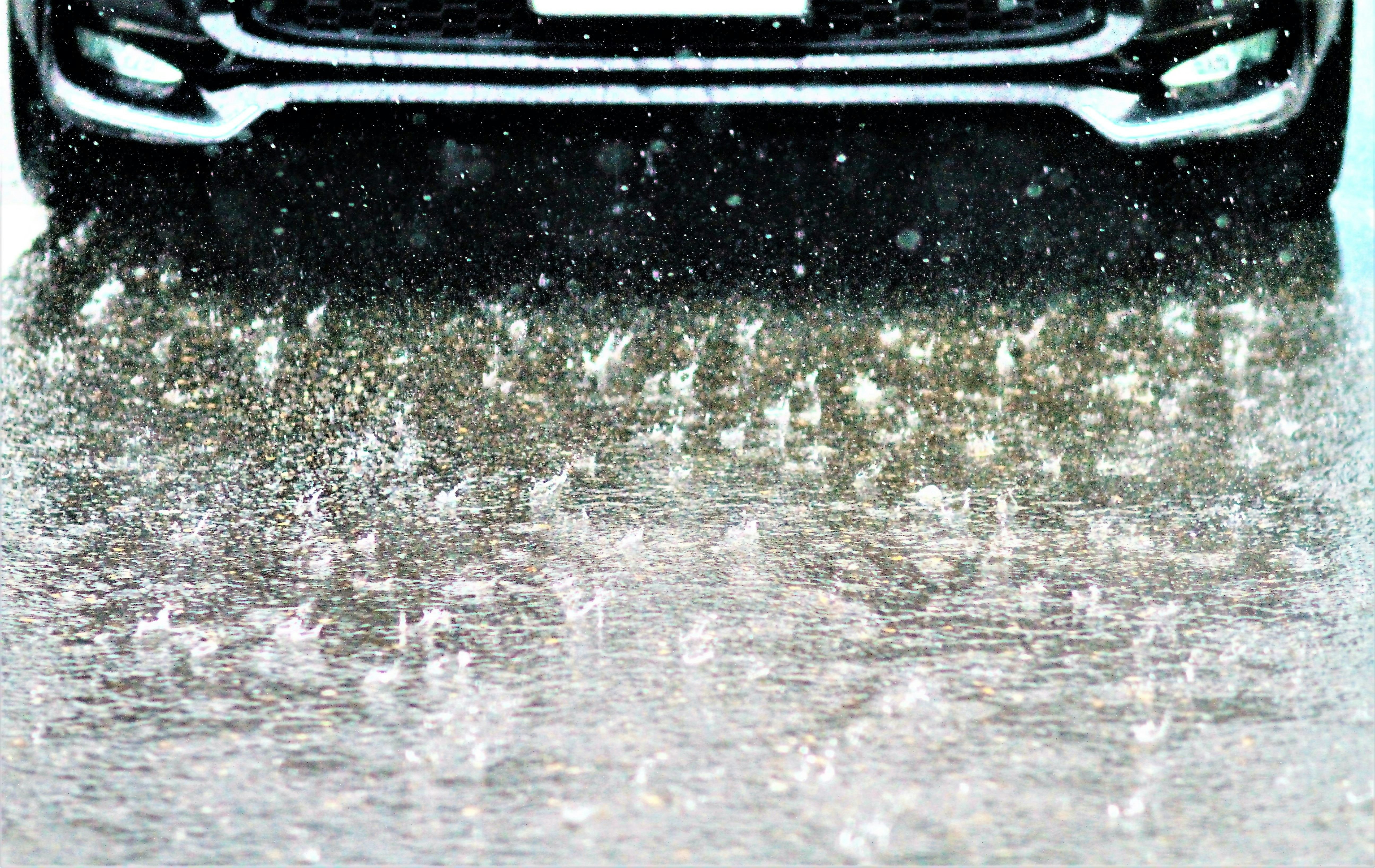 Regen-Spritzwasser und die Vorderseite eines Autos mit Wassertropfen