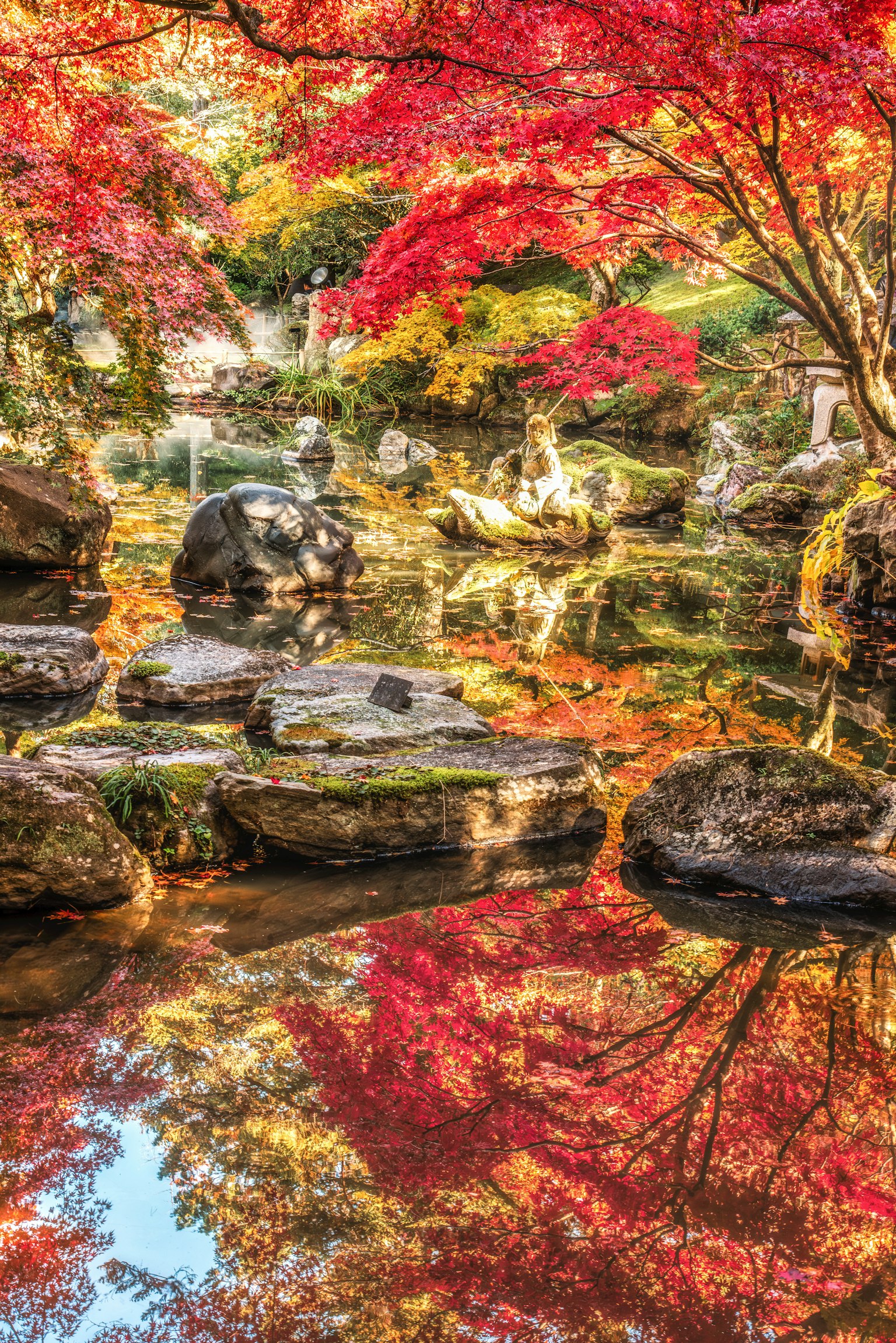美しい紅葉が映る池の風景 石や木々が彩りを添える