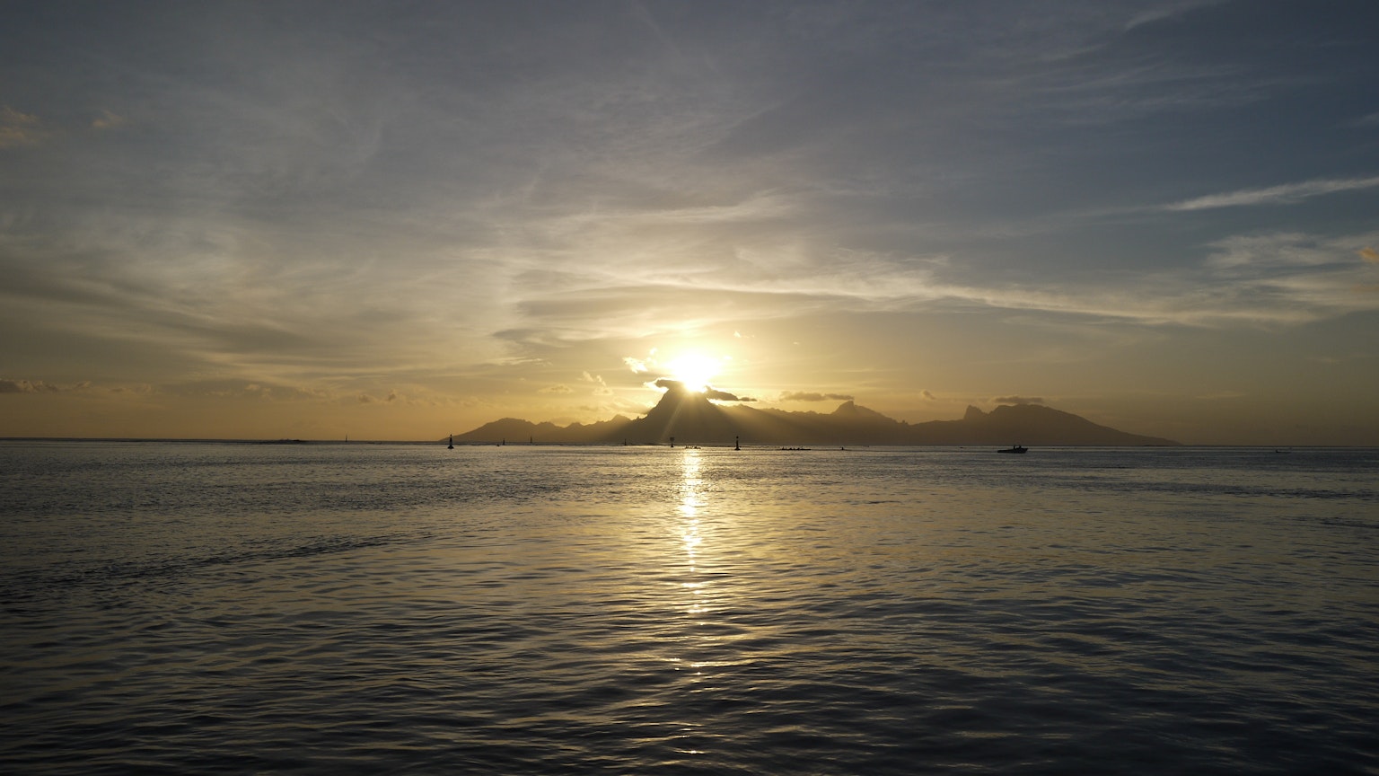 Un coucher de soleil sur l'océan avec des nuages et de l'eau scintillante