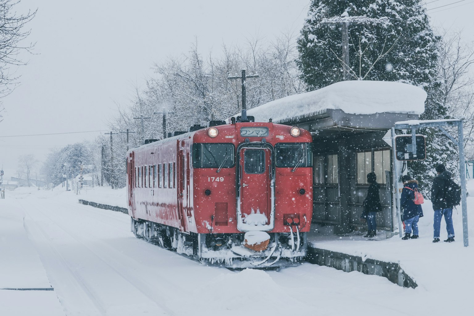 雪覆盖的车站上停着的红色列车和等待的乘客