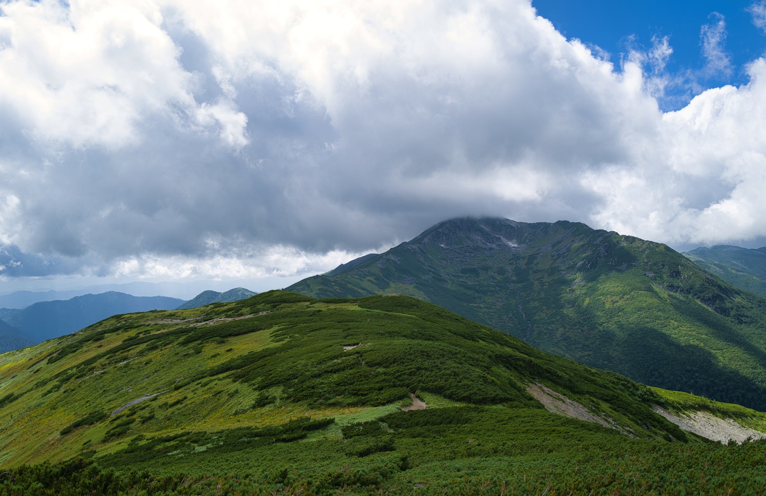 郁郁葱葱的山丘与山脉背景和多云的天空