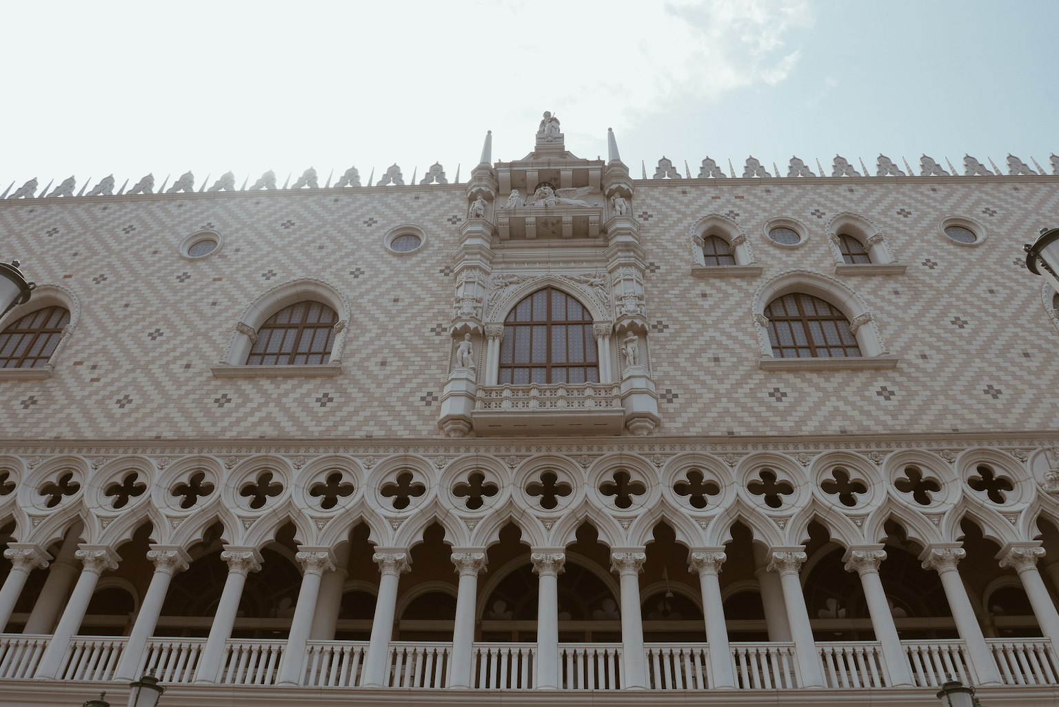 Façade d'un bâtiment décoratif blanc avec des colonnes et des motifs floraux à la base Des fenêtres en arc ajoutent de l'élégance