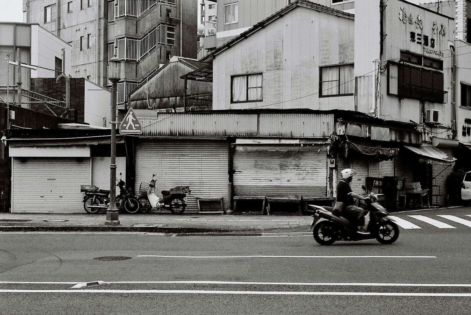 Black and white street scene featuring old buildings and parked motorcycles