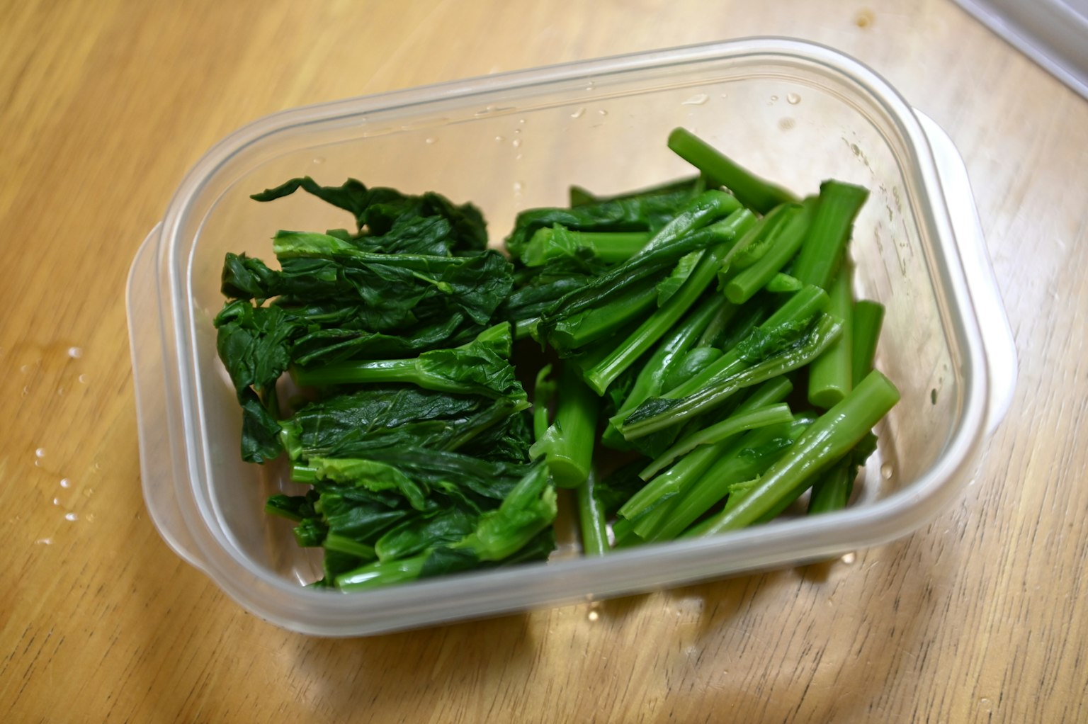 装有绿色蔬菜的容器放在木制表面上