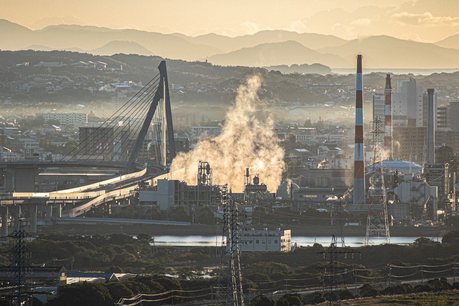Área industrial con humo y fondo de atardecer