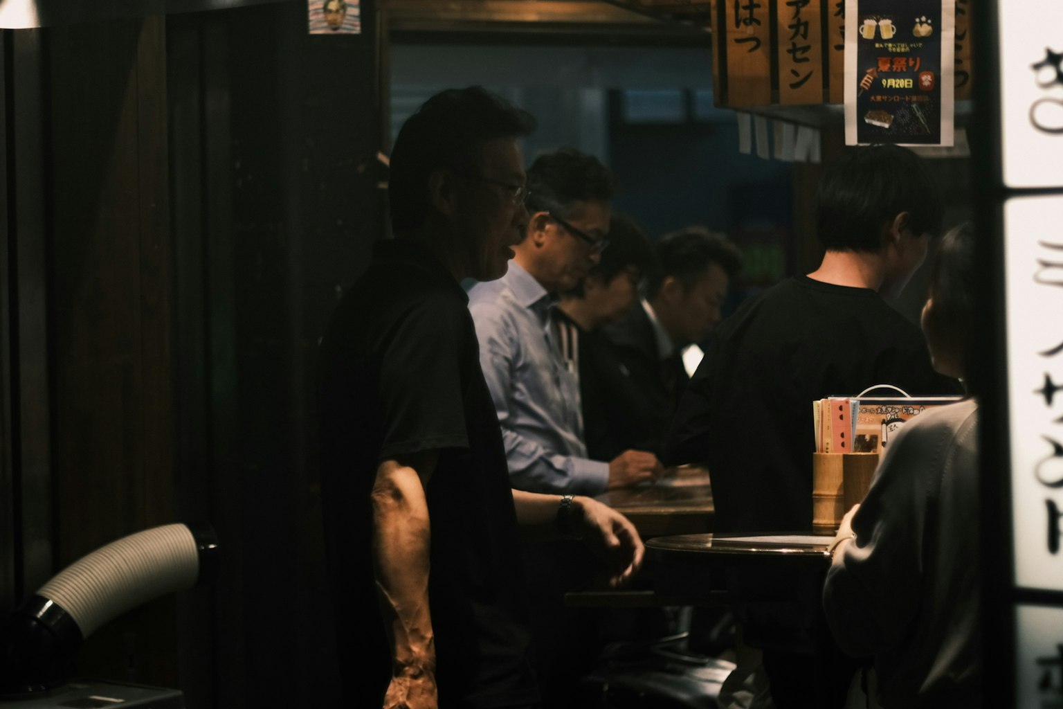 Nội thất của một izakaya ánh sáng mờ với mọi người tụ tập