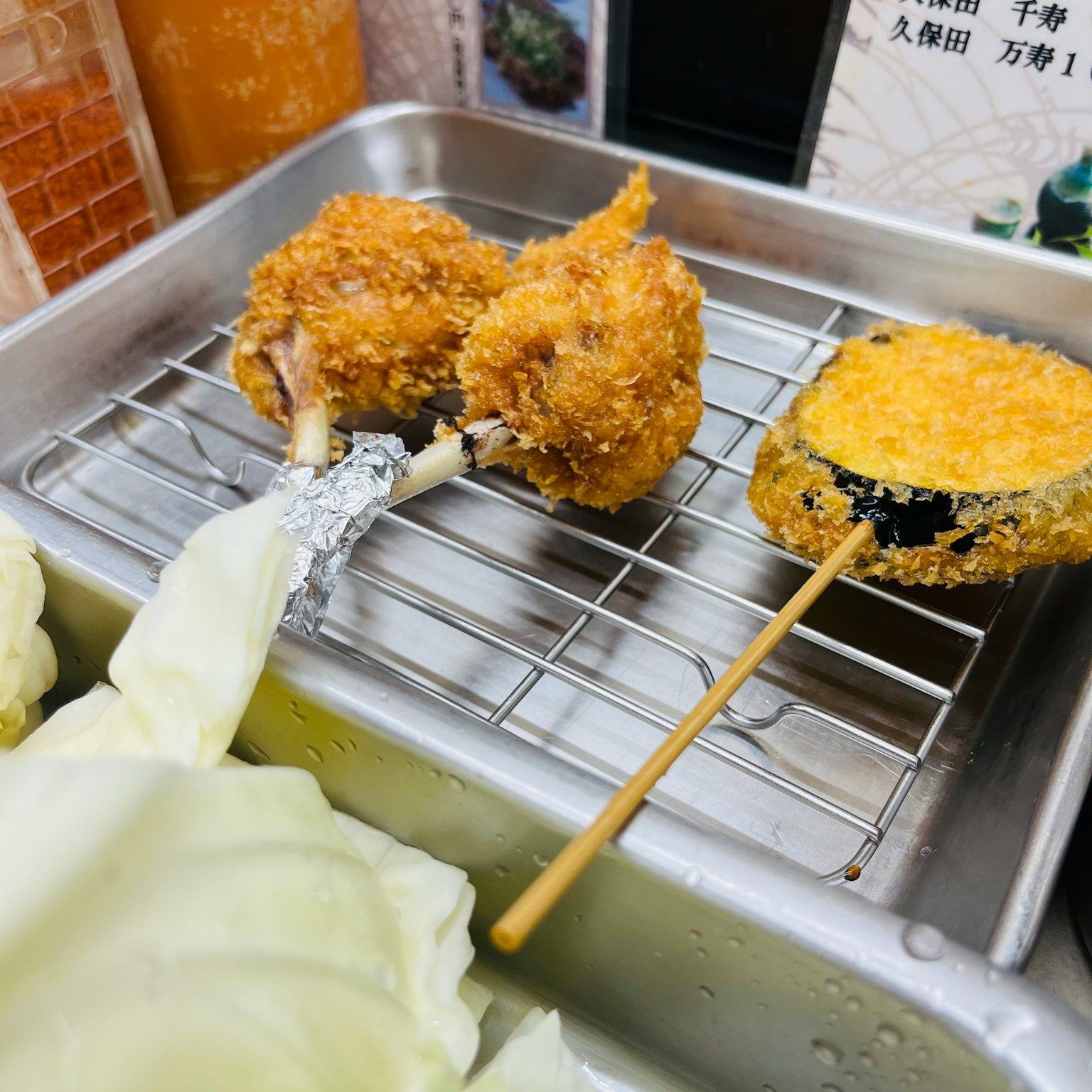 炸食拼盘，带有酥脆的鸡肉块和串烧蔬菜，以及卷心菜叶