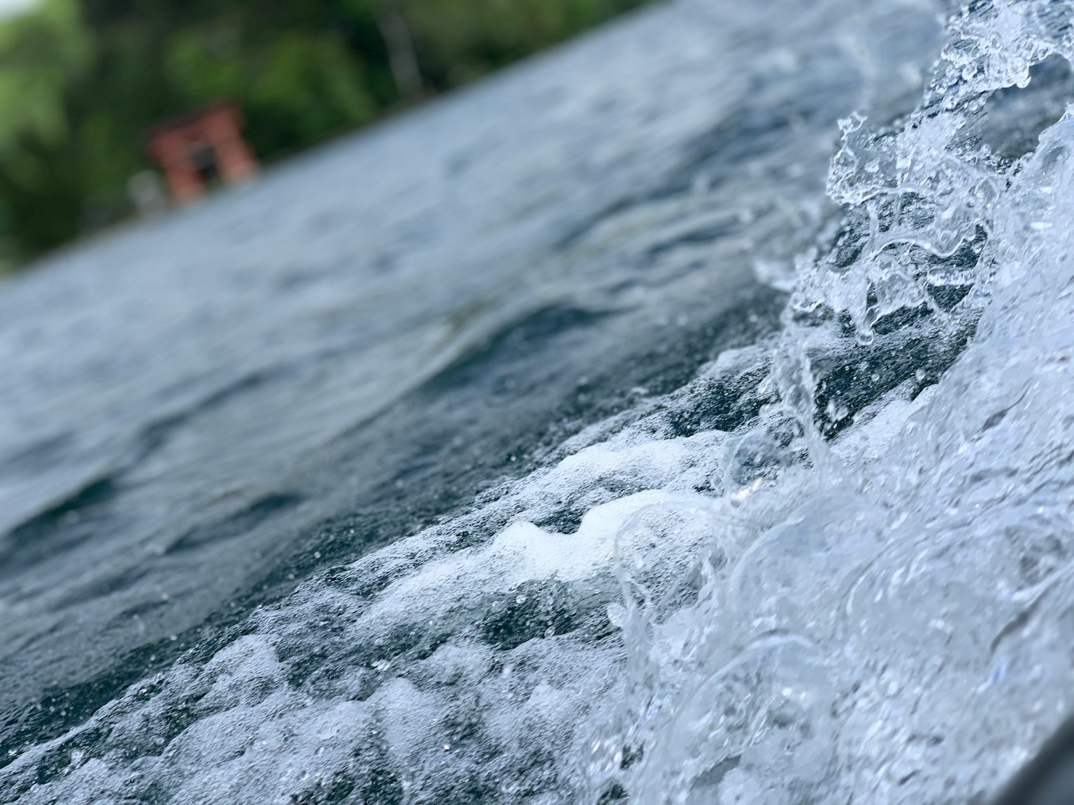 Nahaufnahme von Wasserwellen und Schaum mit grünem Hintergrund
