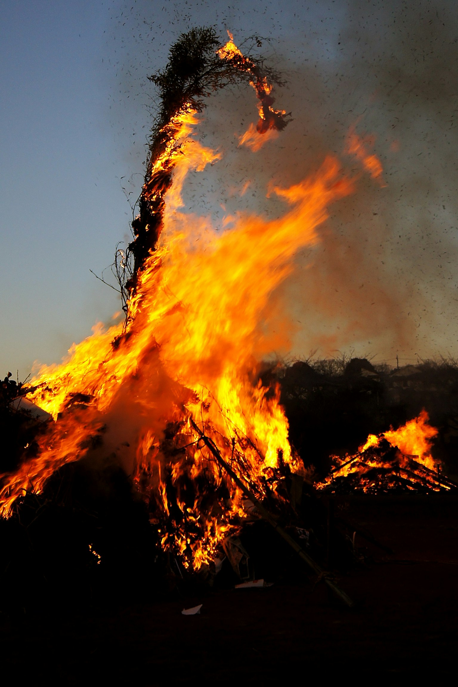 Flammen steigen gegen einen blauen Himmel mit Rauch