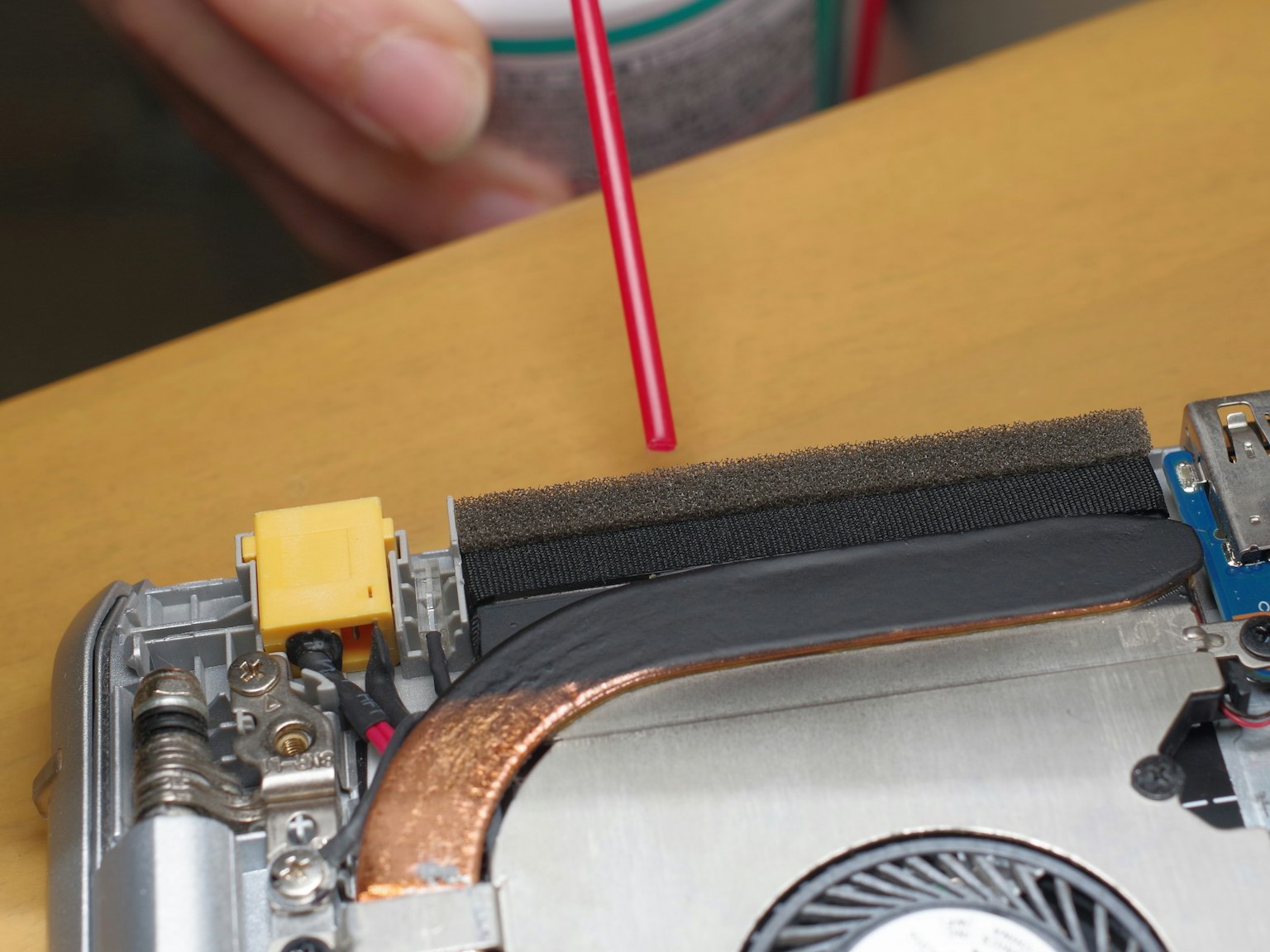 Una mano che punta con uno strumento rosso all'interno di un dispositivo elettronico