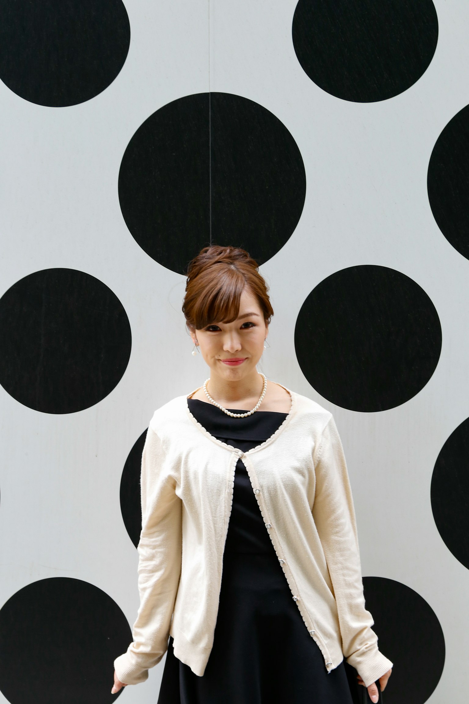 Portrait of a woman standing in front of a black dot wall