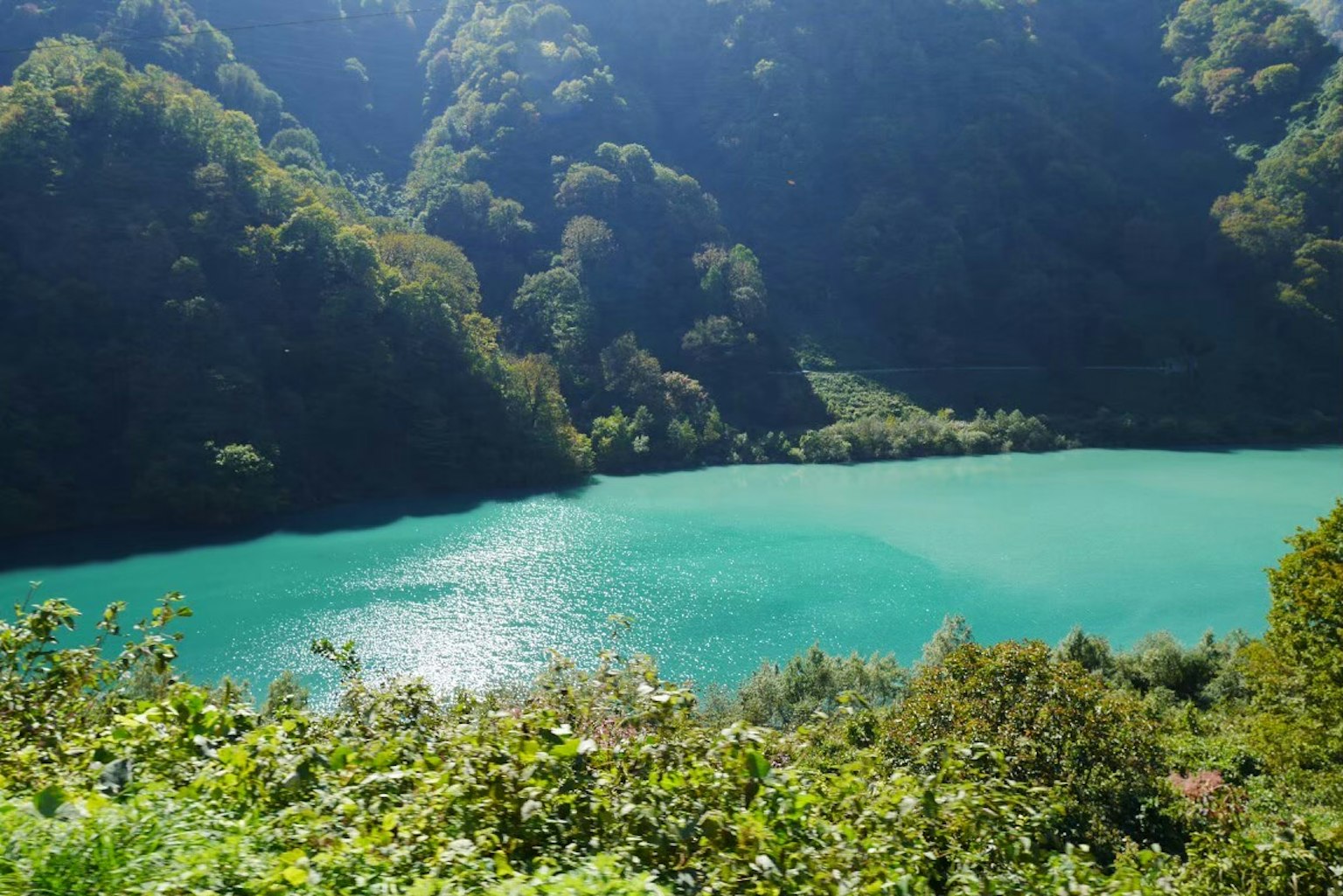Une vue panoramique d'un lac turquoise entouré de montagnes verdoyantes