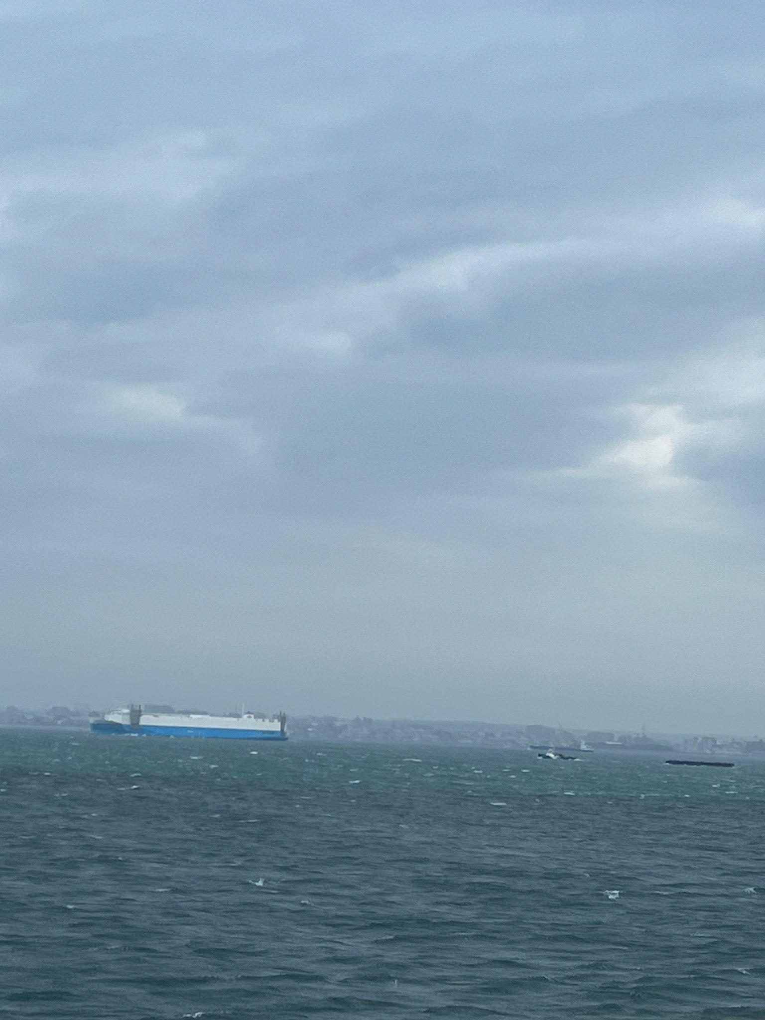 Un barco de carga azul en un mar nublado