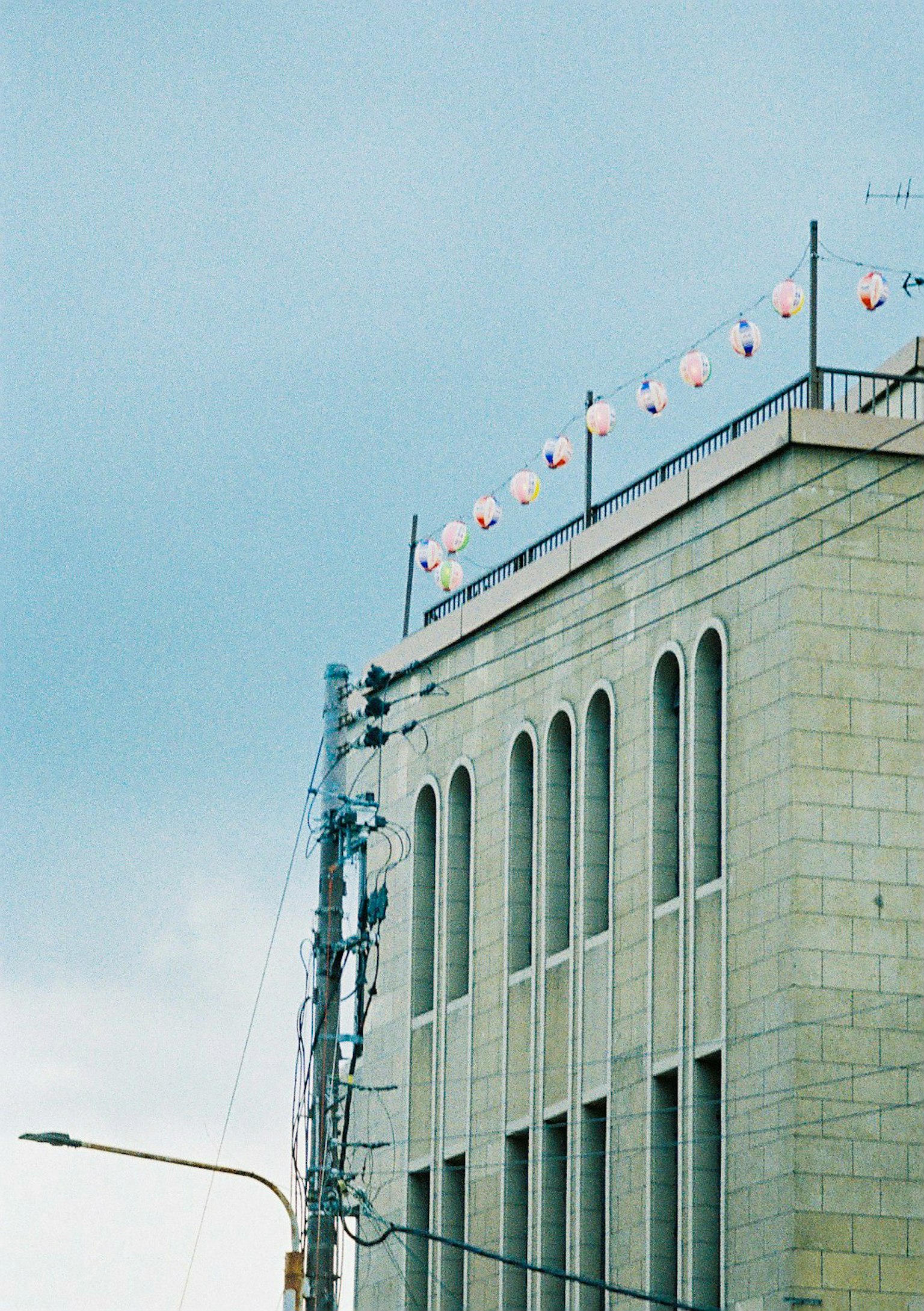 Stone building with lanterns on the rooftop under a blue sky