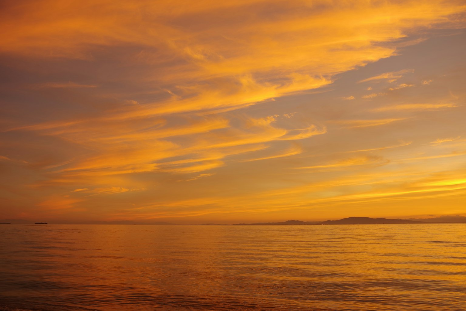 Tramonto sull'oceano con nuvole arancioni e superficie d'acqua calma
