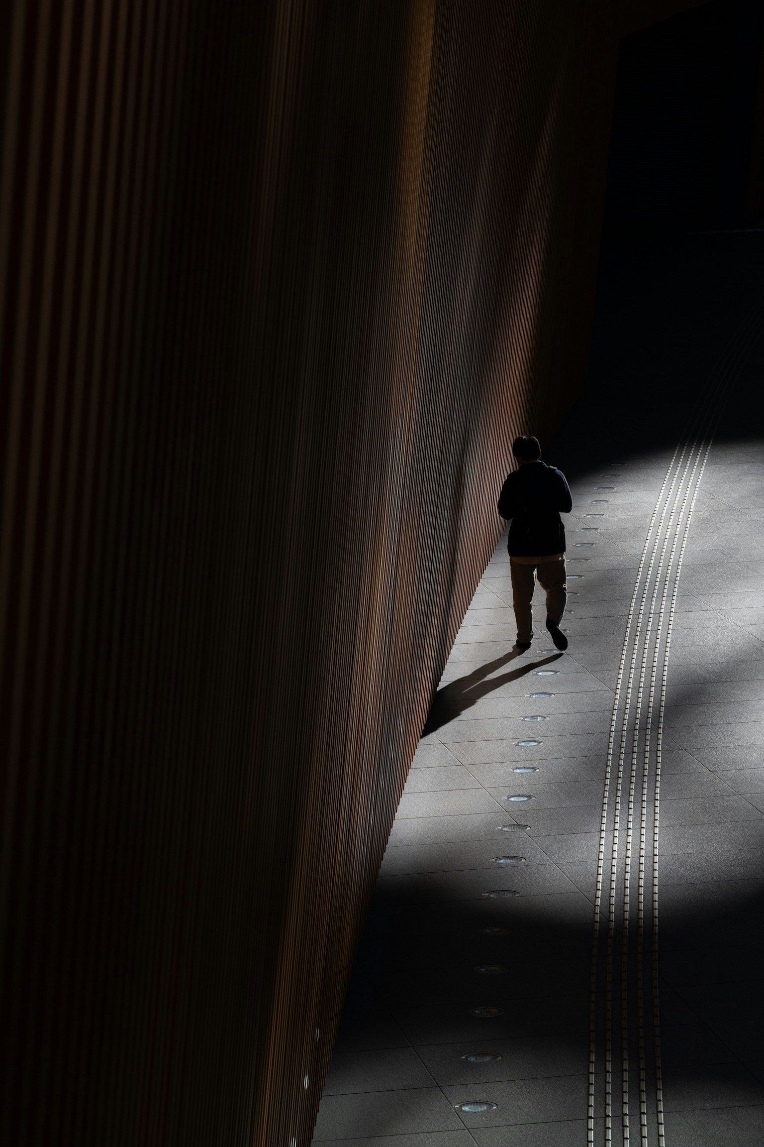 Silueta de una persona caminando en un pasillo oscuro con contraste de luz