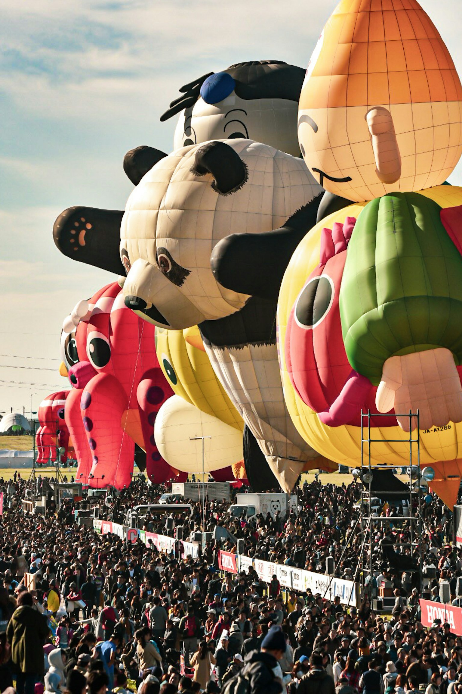 カラフルな熱気球が空に浮かぶ祭りの風景 大勢の観客が見守る中でのバルーンイベント