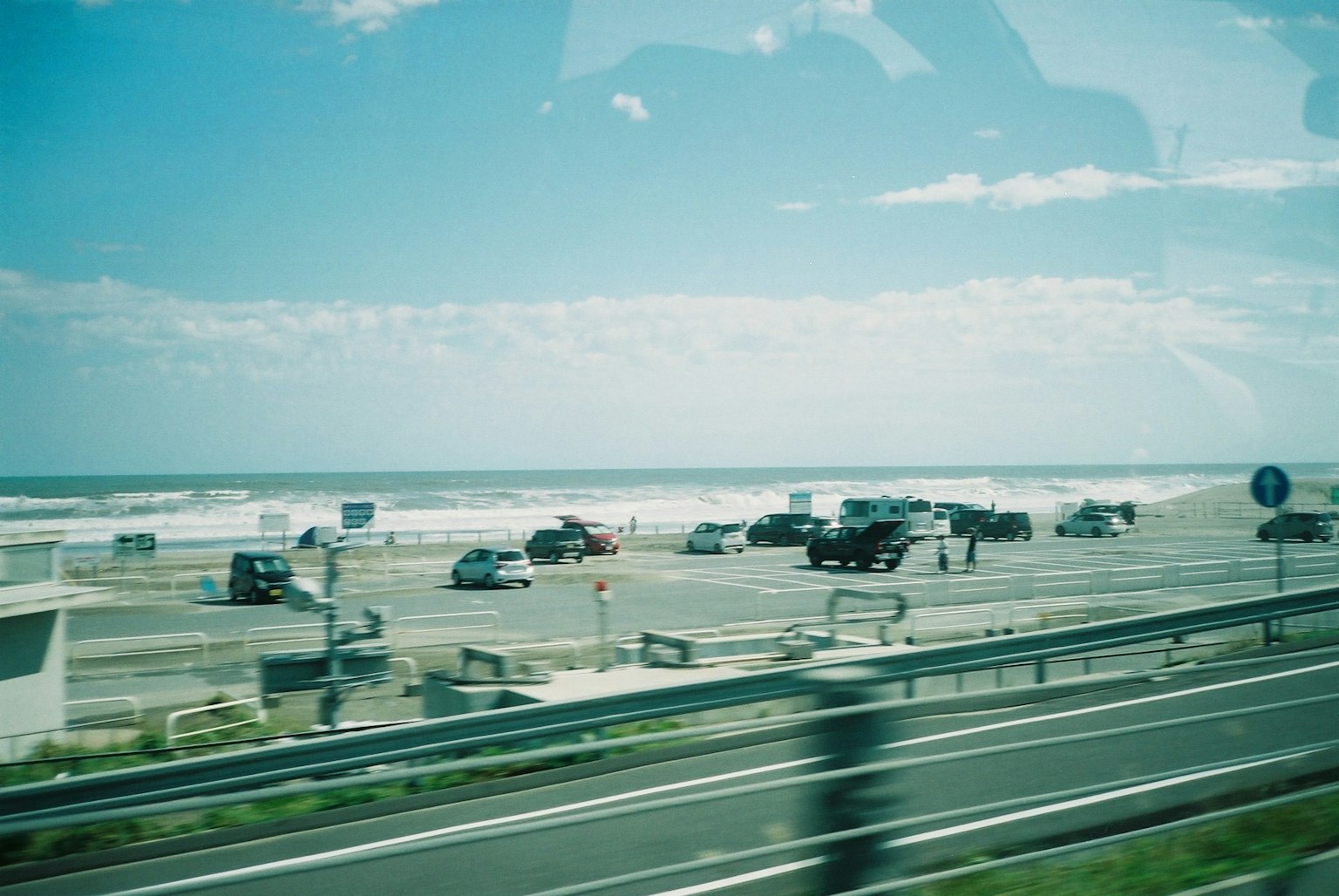 Coches estacionados cerca de la playa con olas del océano de fondo