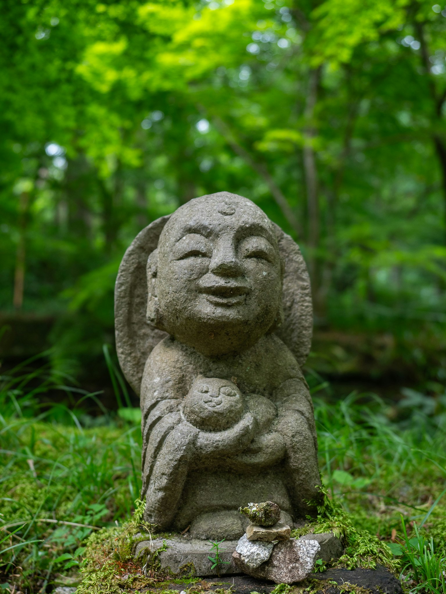 Una statua di pietra sorridente si erge in una foresta lussureggiante