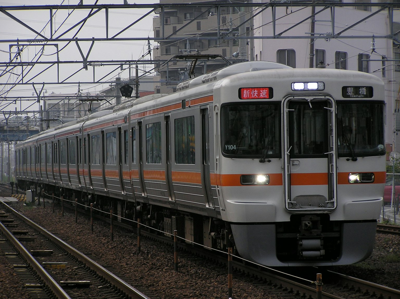 Japanese train with orange stripes running on tracks