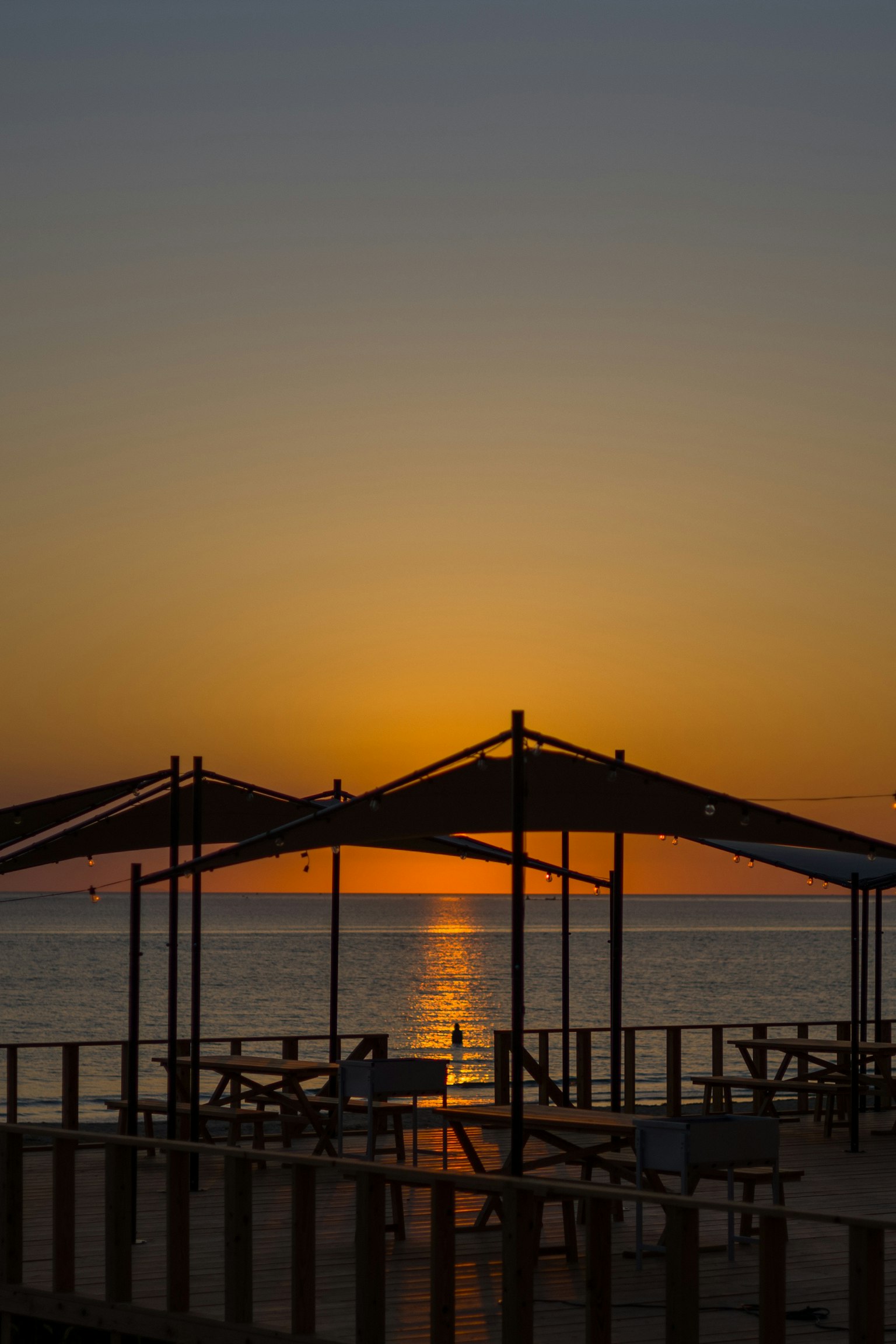 Silhouette von Unterständen gegen einen Sonnenuntergang über dem Meer