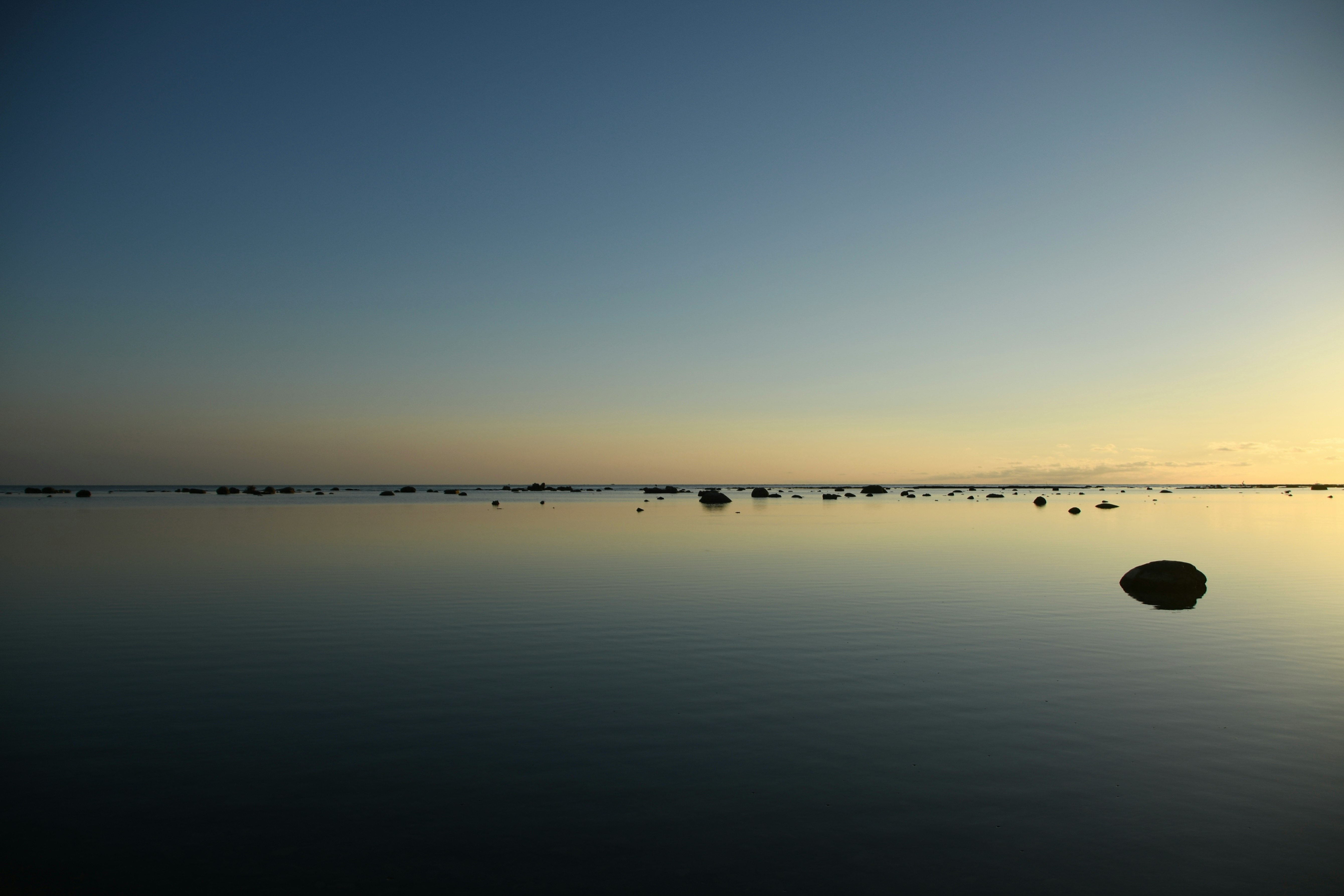 夕暮れの静かな海面と沖合の浮き