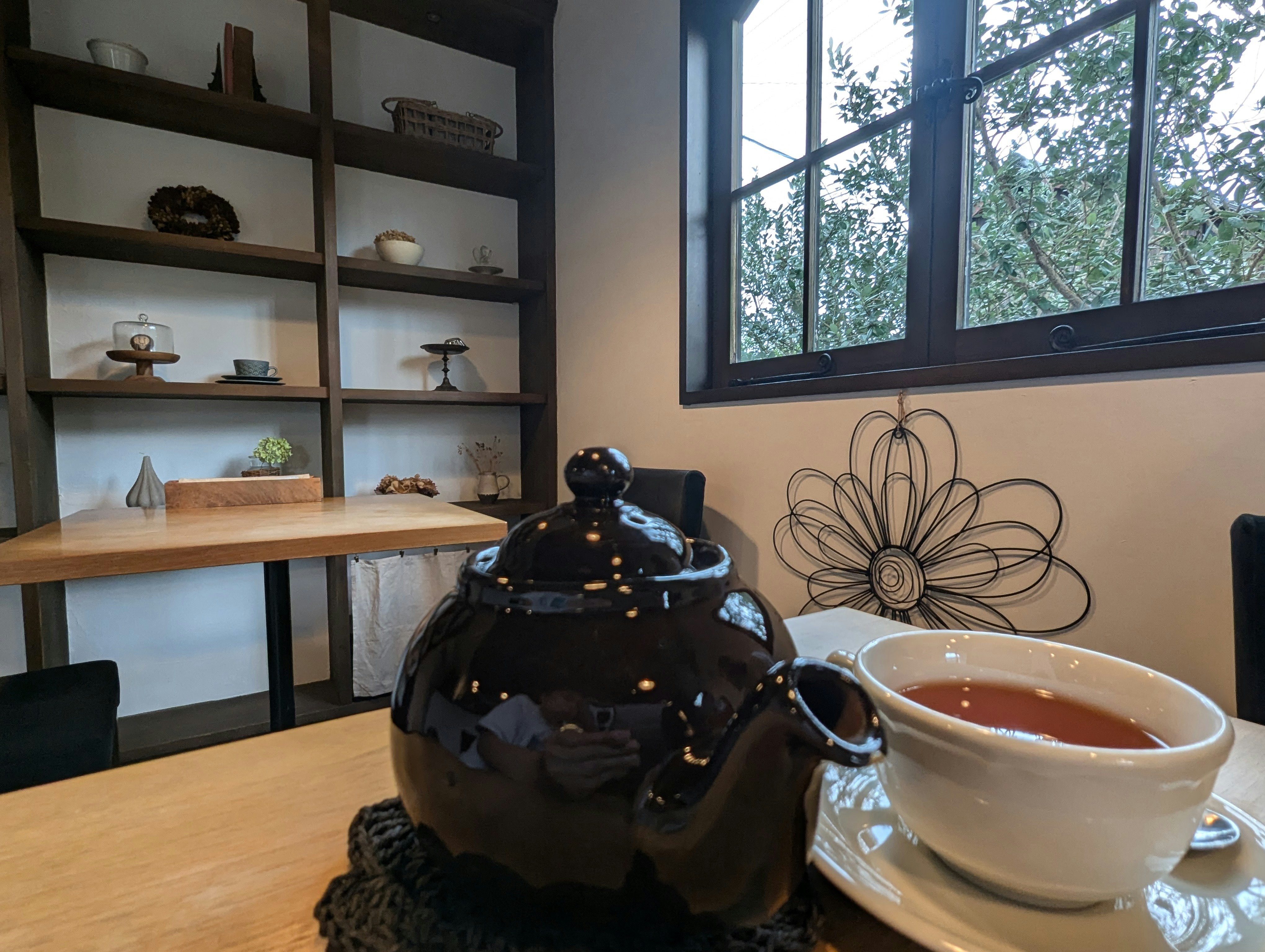 窓辺のカフェで湯気の立つ紅茶とティーポット